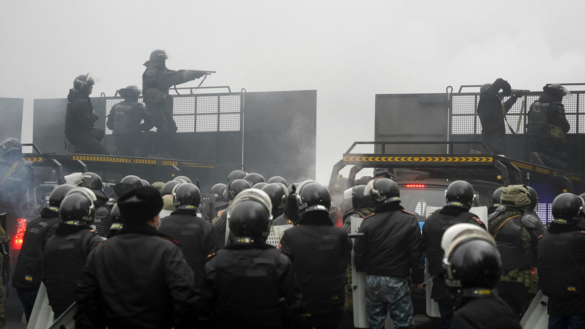 Bereitschaftspolizisten in Kasachstan blockieren eine Straße, um Demonstranten aufzuhalten. 
