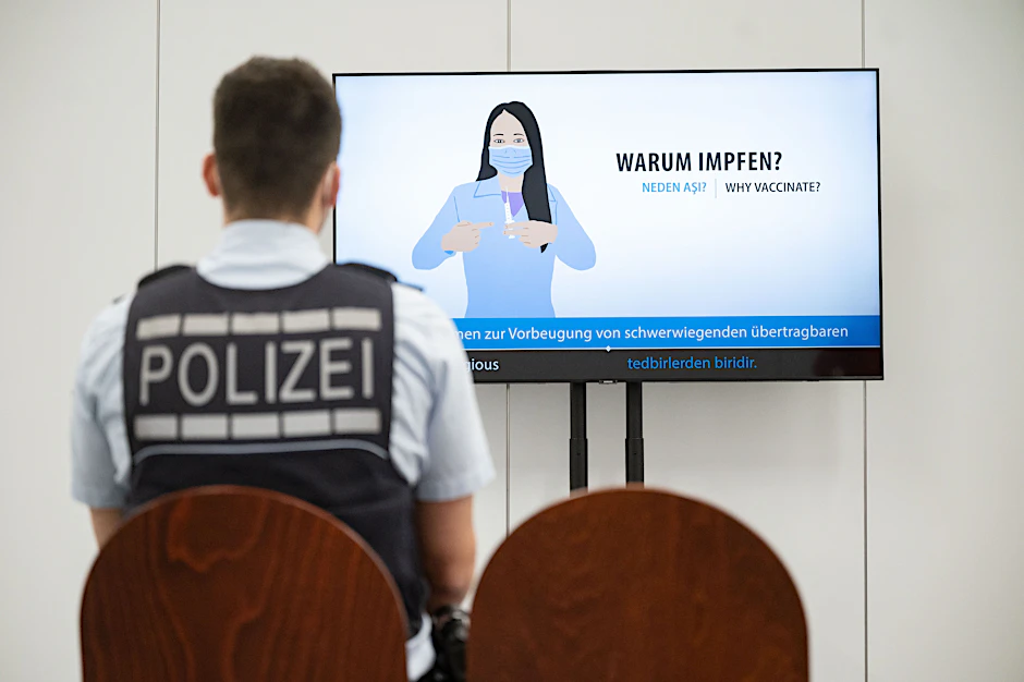 Ein Polizeibeamter verfolgt einen Aufklärungsfilm über die Corona-Impfung.