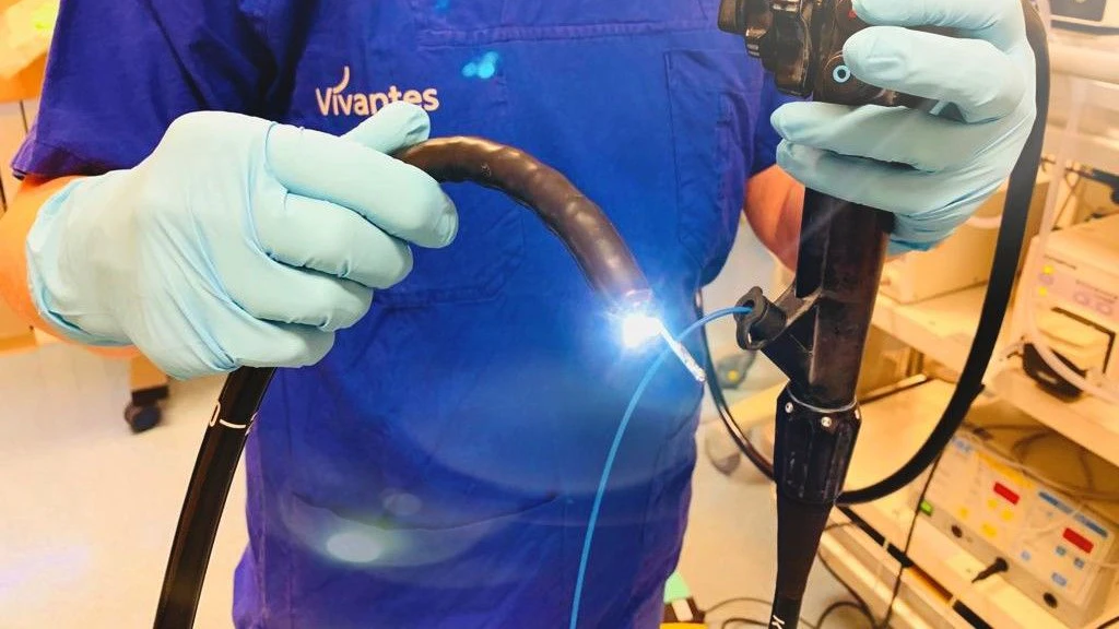 Der schwarze Schlauch ist das Koloskop, mit dem die Darmspiegelung vorgenommen wird. Rechts im Bild ist eine Biopsiezange zu sehen, die in den Arbeitskanal des Untersuchungsgerätes führt.