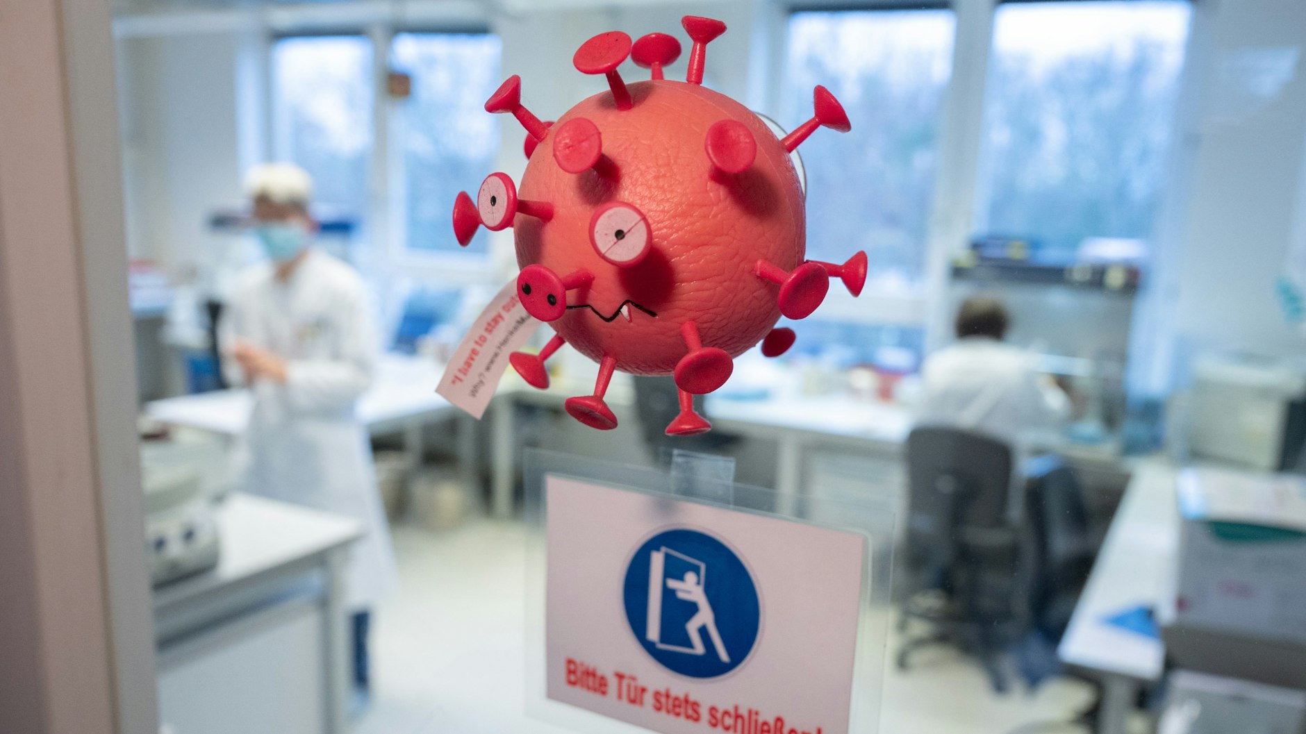 Eine Figur in Optik eines Virus hängt an der Tür vom PCR-Labor im Niedersächsischen Landesgesundheitsamt. Hier wird täglich auch auf Omikron getestet.