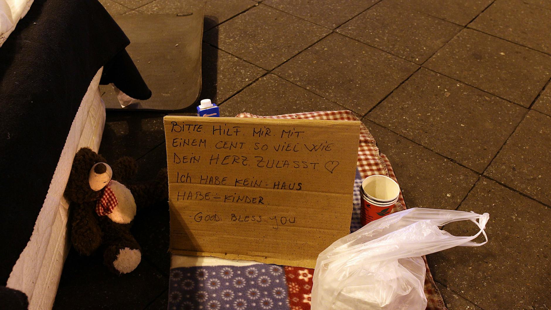 Ein Obdachloser hat ein Pappschild aufgestellt und bittet um Spenden.