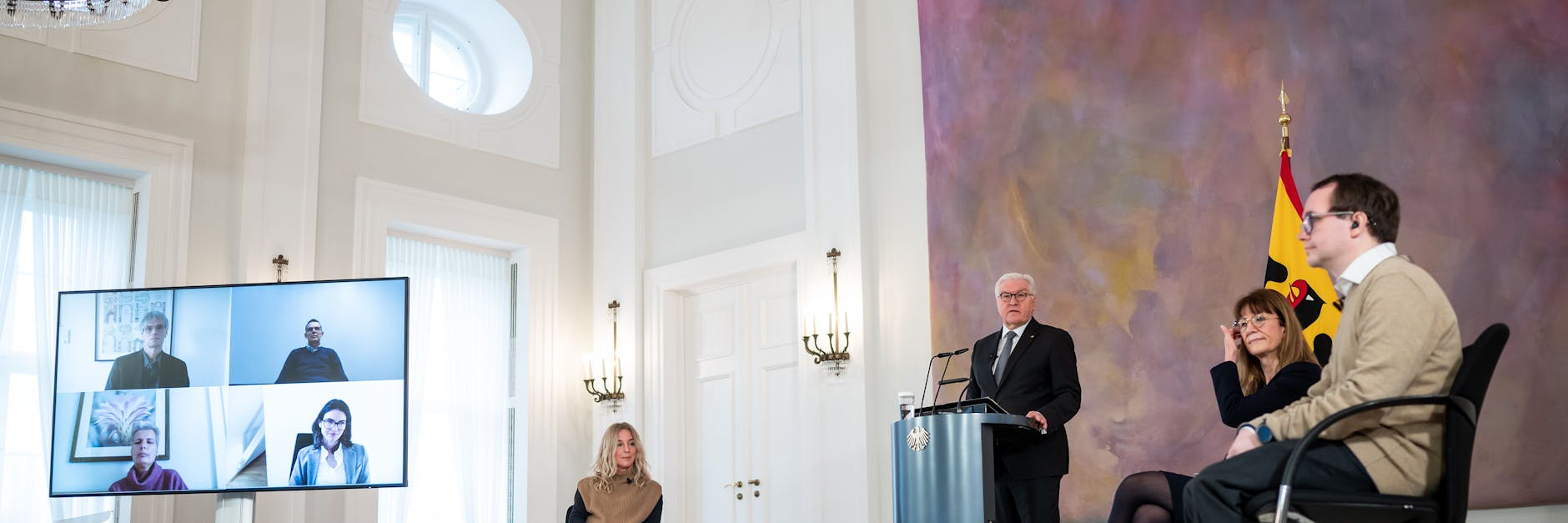 Bundespräsident Frank-Walter Steinmeier (3.v.r.) diskutiert mit Gästen im Schloss Bellevue, sowie digital zugeschalteten Teilnehmerinnen und Teilnehmern. 