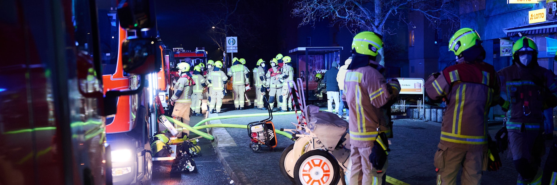 Feuerwehrleute stehen am frühen Mittwochmorgen vor Einsatzfahrzeugen in der Maulbeerallee im Berliner Stadtteil Staaken. Sie mussten mehrere brennende Keller löschen.