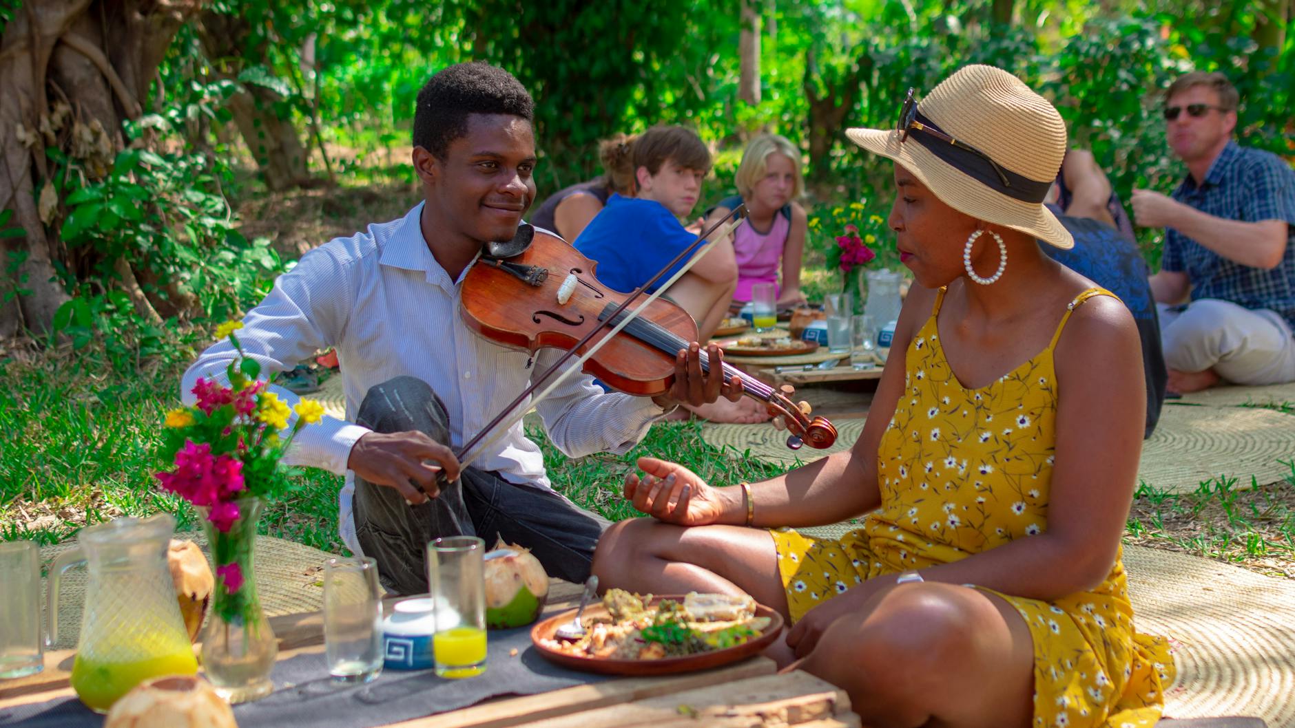 Ein Geiger spielt einer Touristin bei einem Picknick auf einer Öko-Farm ein Lied vor.