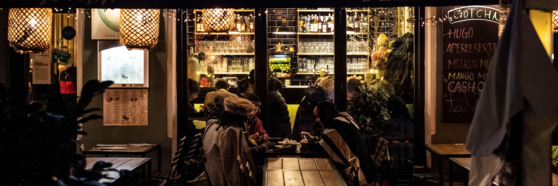 Gäste sitzen in und vor einem asiatischen Restaurant in der Simon-Dach-Straße. Seit Sonnabend gilt in Berlin in Restaurants, Kneipen und Cafés die 2Gplus-Regel.