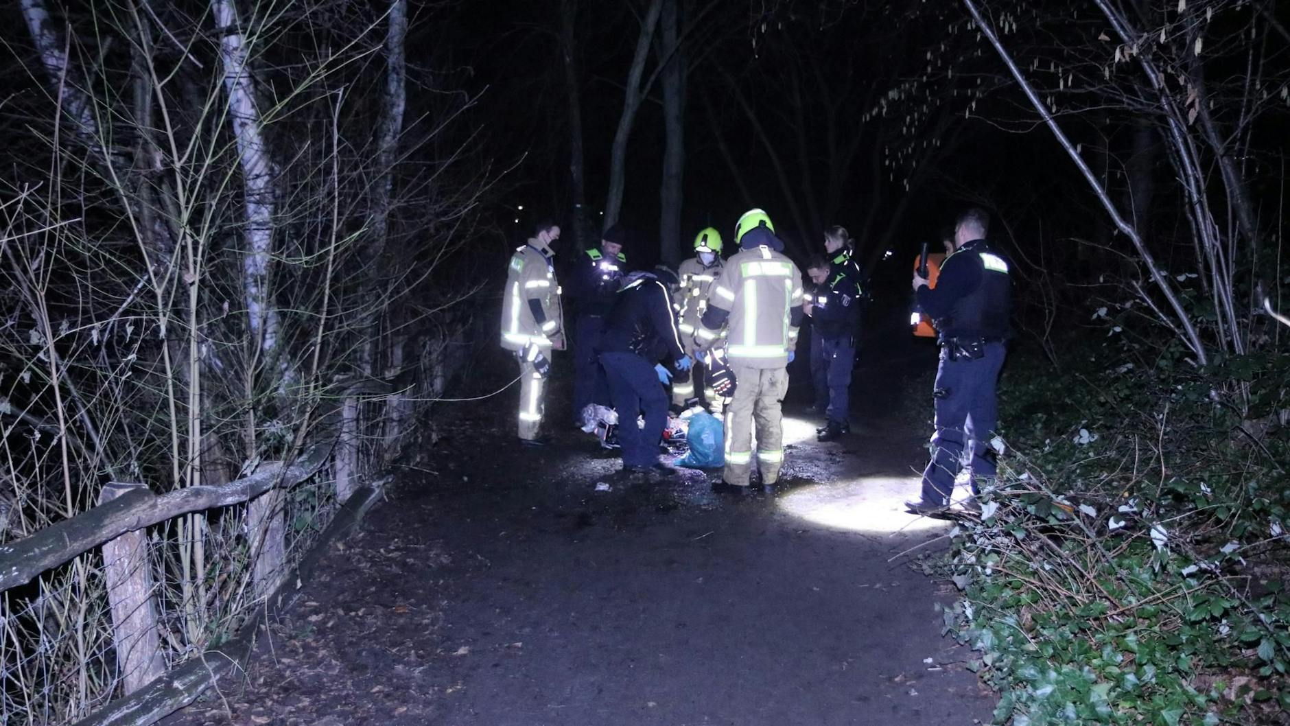 Beamten durchsuchen am Unfallort die Sachen des Flüchtigen, der zuvor aus einem eiskalten Teich gerettet wurde.