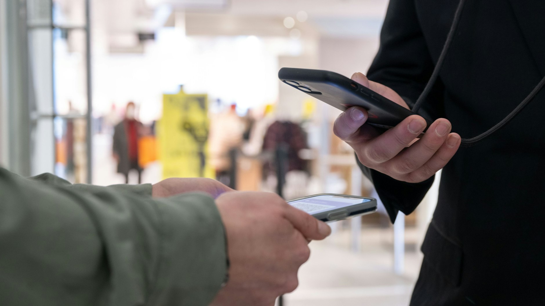 Ein Mitarbeiter eines Kaufhauses kontrolliert am Eingang mit einem Smartphone die Einhaltung der 2G-Regel und den Impfnachweis einer Kundin.