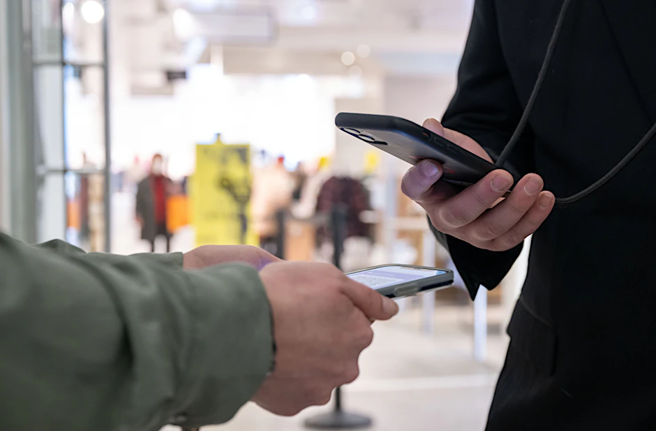 Ein Mitarbeiter eines Kaufhauses kontrolliert am Eingang mit einem Smartphone die Einhaltung der 2G-Regel und den Impfnachweis einer Kundin.
