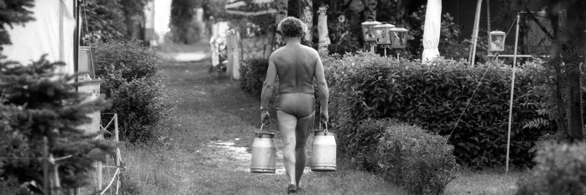 Im August 1986: Ein Mann trägt Milcheimer auf einem Zeltplatz in Radeburg.