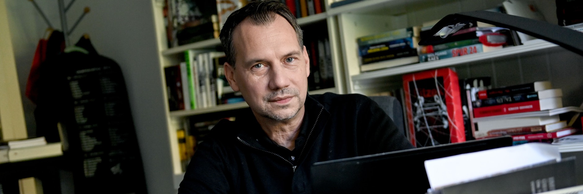 Der Autor Sebastian Fitzek sitzt an seinem Schreibtisch in seinem Arbeitszimmer.