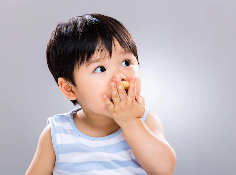 Ein Kleinkind isst. Einer US-Studie zufolge kann die Aufnahme von Erdnüssen in den Speiseplan von Kleinkindern Allergien gegen Hülsenfrüchte lindern.