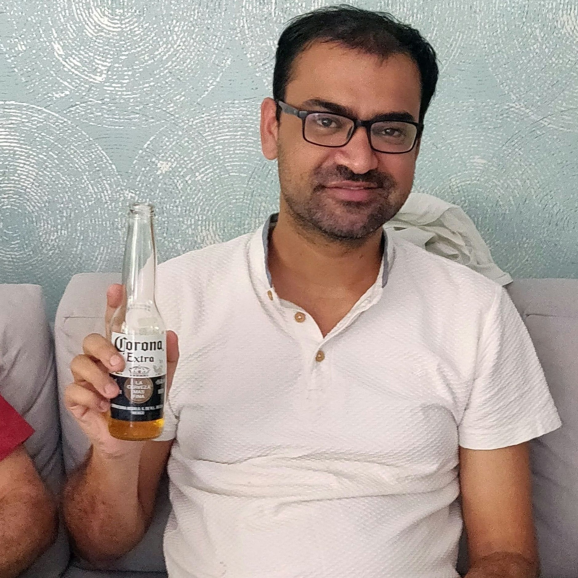 Kovid Kapoor hält eine Flasche Corona-Bier in der Hand. Er sei seit 1990 Kovid-positiv – also seit seiner Geburt.