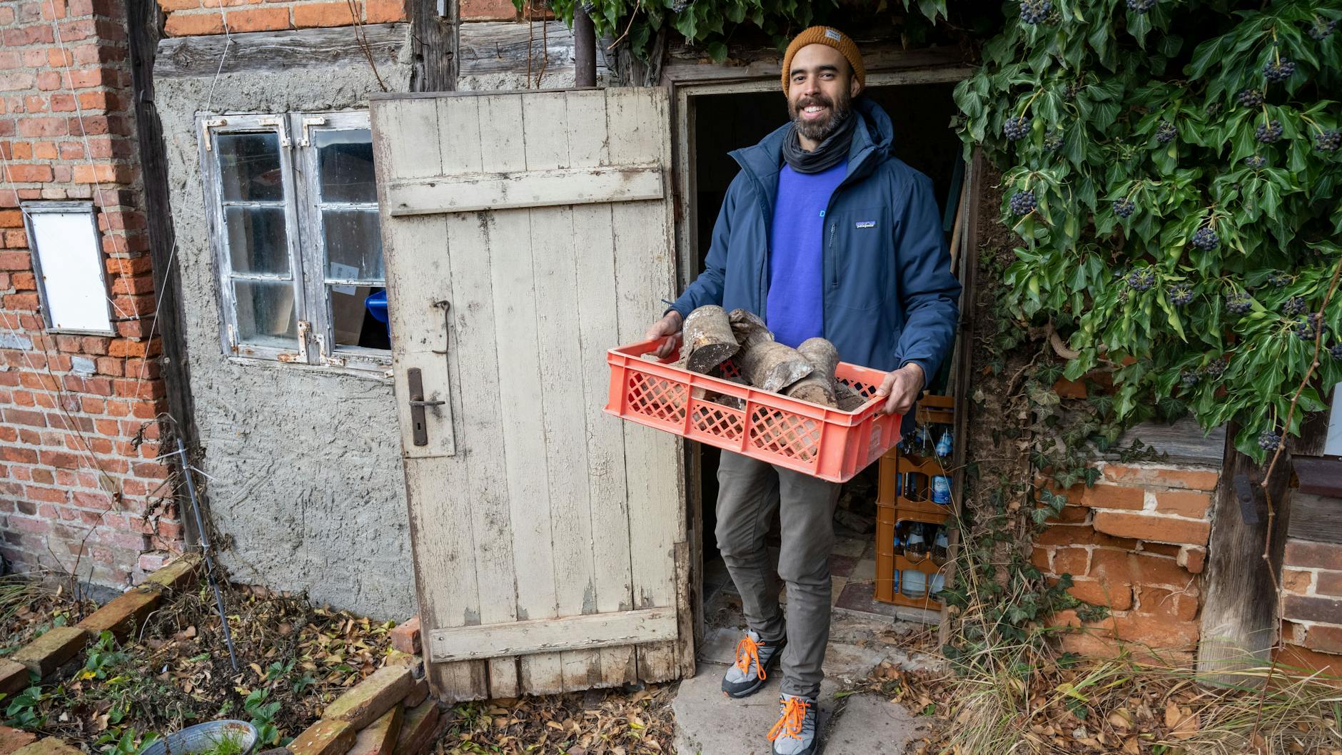 Rolando Gonzalez kommt mit einer Feuerholzkiste aus dem Haus in Loitz.