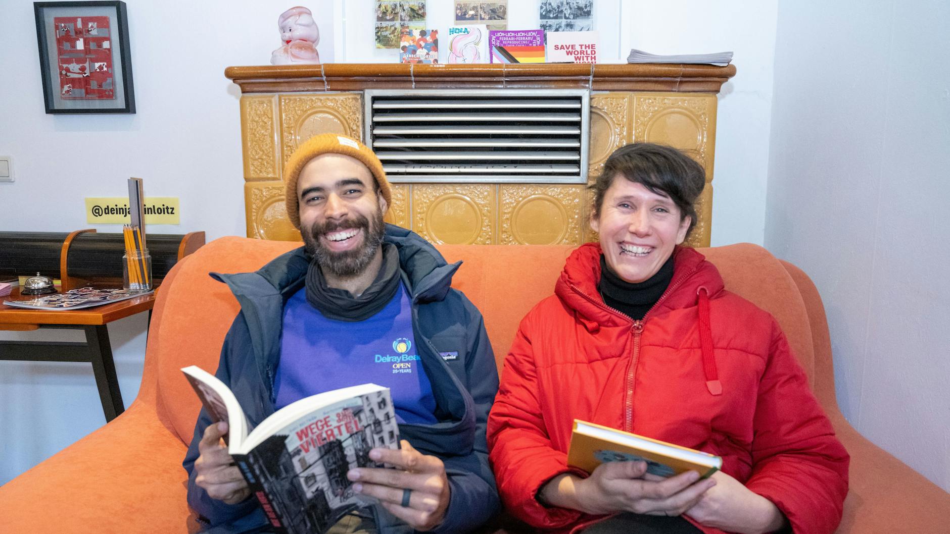Annika Hirsekorn und Rolando Gonzalez sitzen in ihrer Comic-Bibliothek auf einem Sofa.