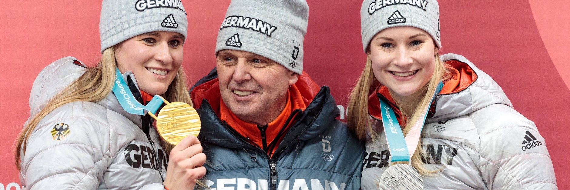 Natalie Geisenberger (l.) und Dajana Eitberger räumten 2018 ab, zeigten stolz ihre Medaillen zusammen mit Bundestrainer Norbert Loch.