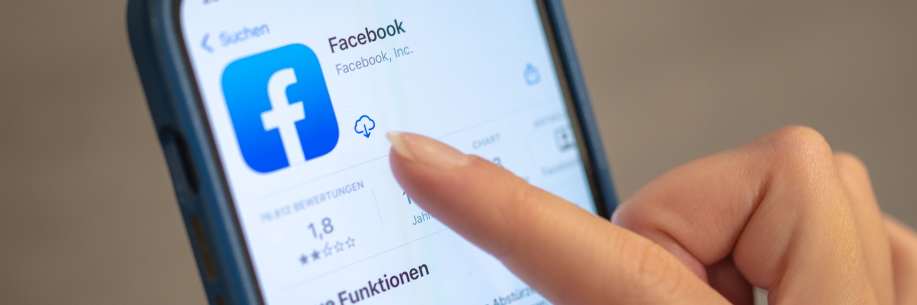 Eine Frau hält ihr Handy in der Hand, auf dem die Facebook-App zu sehen ist.