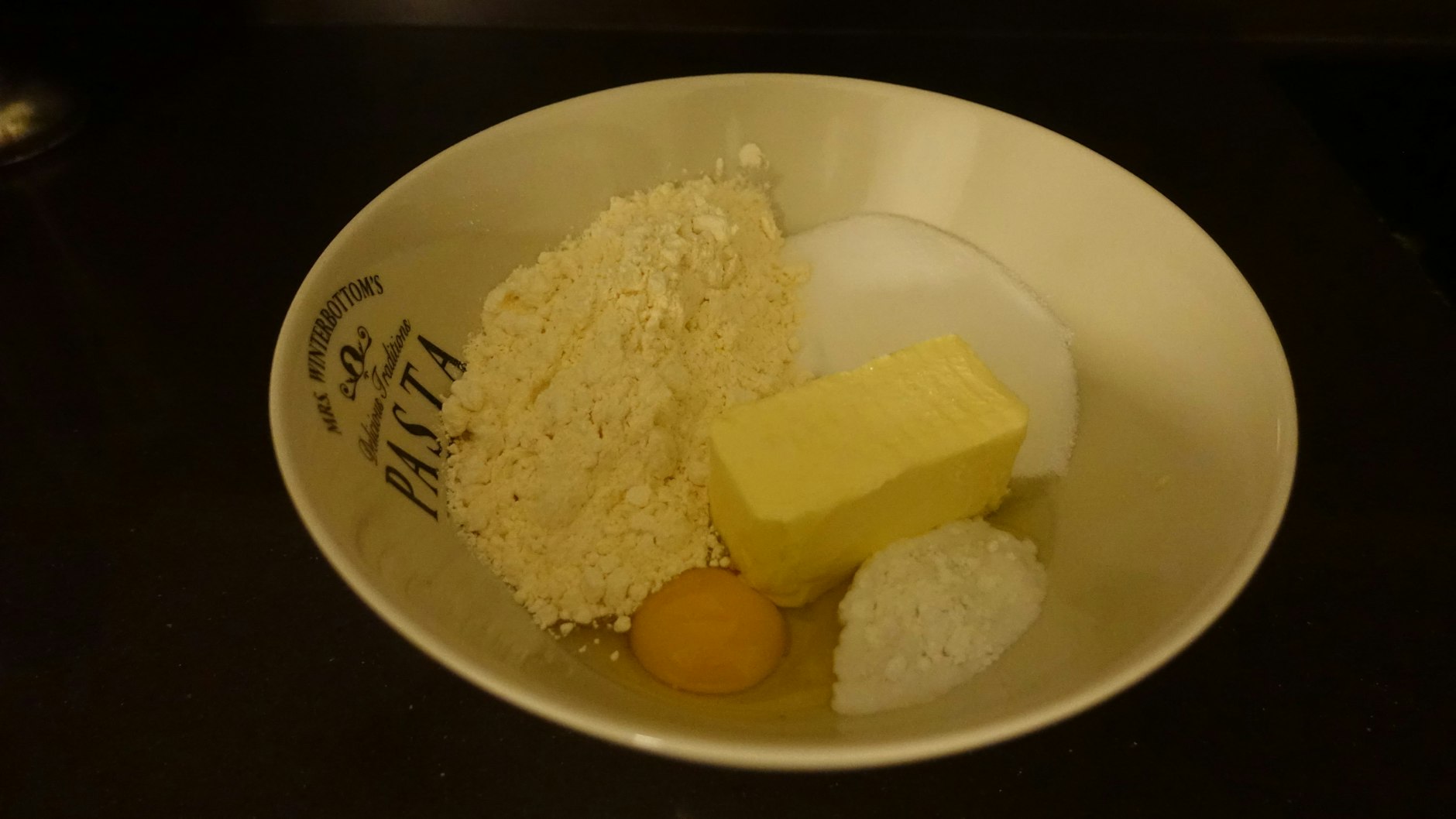 Für den Boden werden Mehl, Backpulver, Zucker, eine Prise Salz, zwei Eier und Butter miteinander verrührt und geknetet.