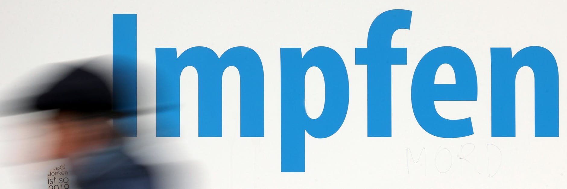 Ein Mann geht vor einem Impfzentrum entlang.