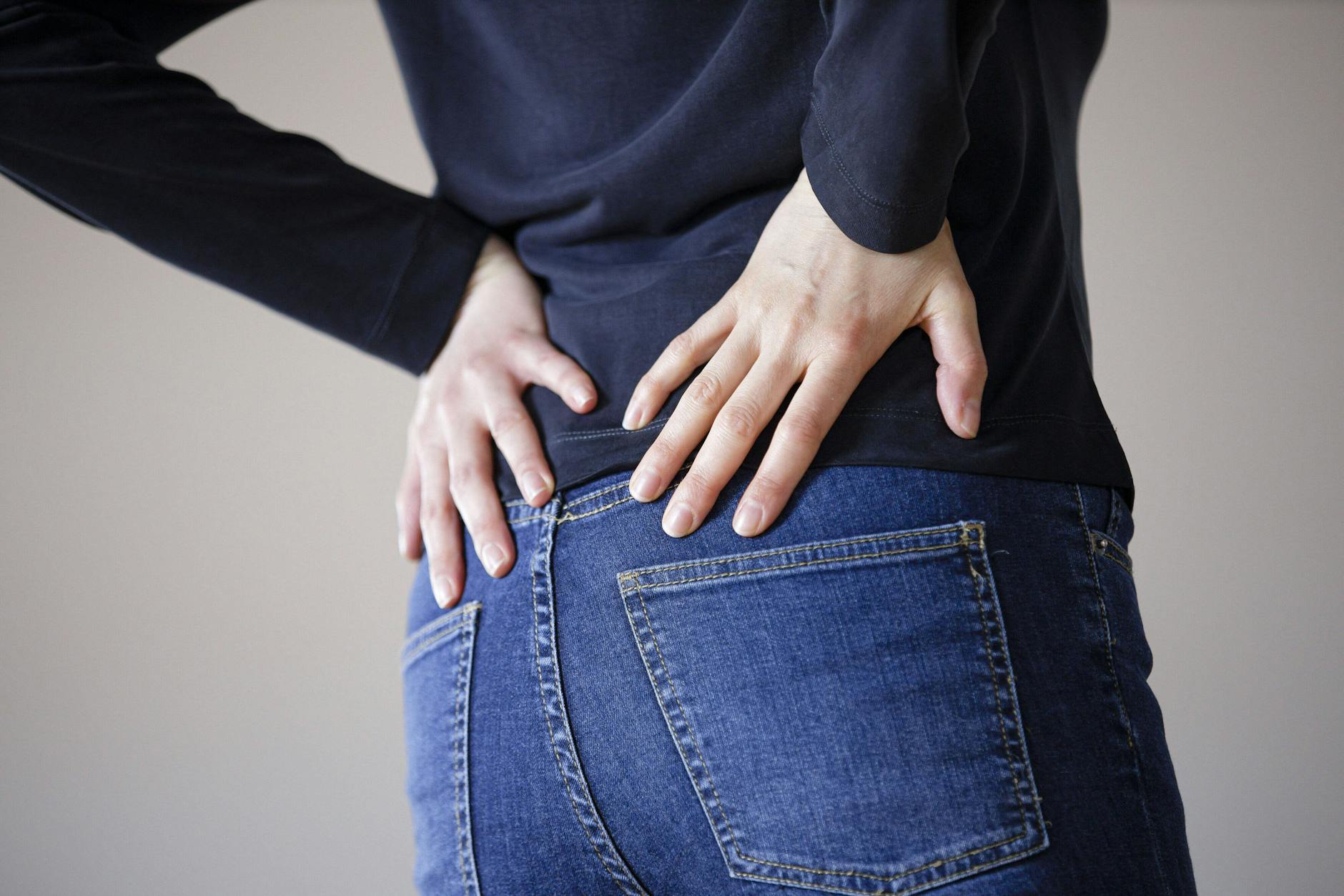 Eine Frau fasst sich mit den Händen an den Rücken. 2020 litten weltweit 619 Millionen Menschen unter Schmerzen im unteren Rücken.