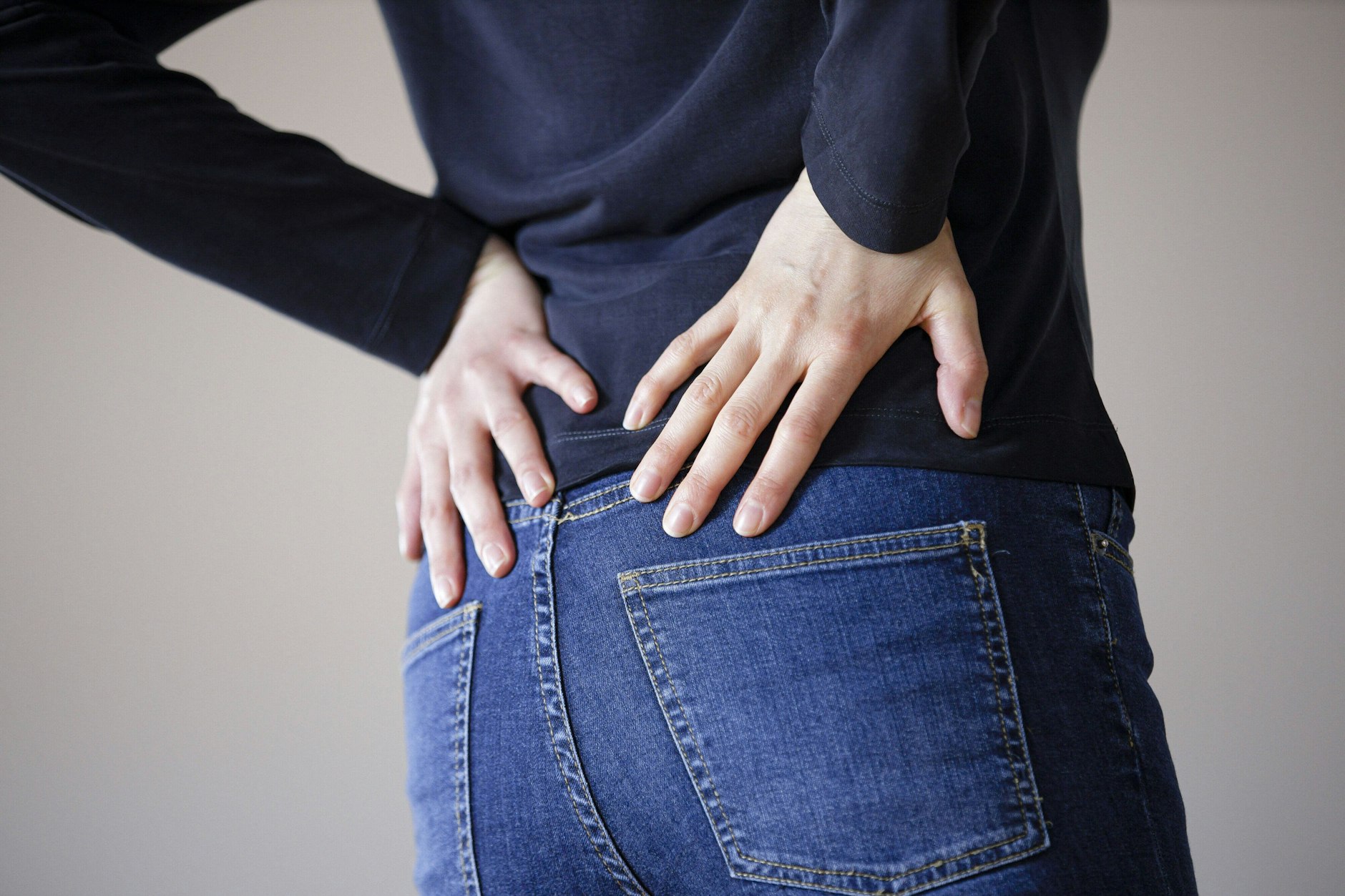 Eine Frau fasst sich mit den Händen an den Rücken. 2020 litten weltweit 619 Millionen Menschen unter Schmerzen im unteren Rücken.