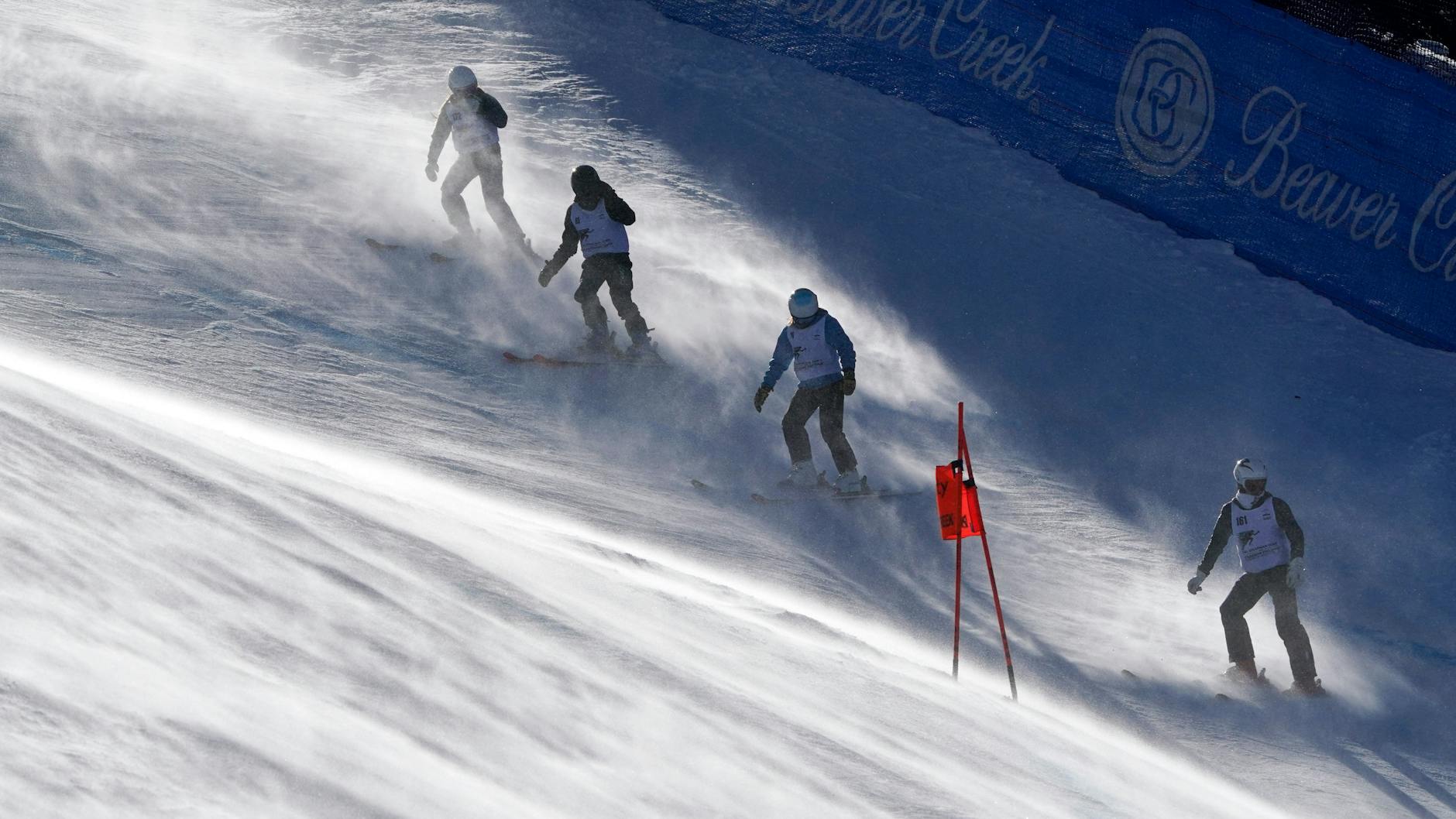 Streckenarbeiter kämpfen auf der Piste der Herren-Abfahrt mit dem starken Wind.