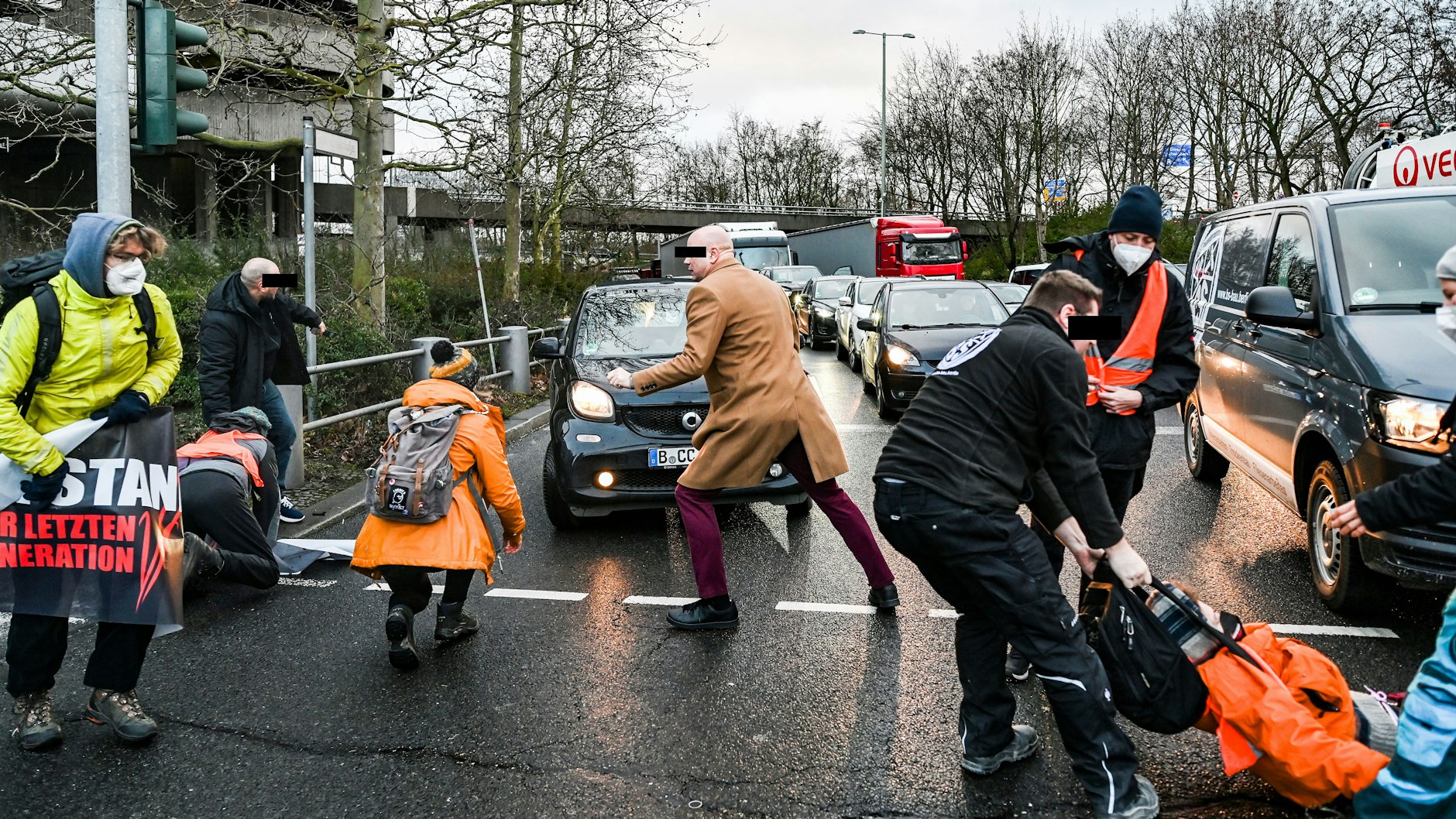 Der Mann im beigen Mantel schubste die Person in der orangenen Jacke um.