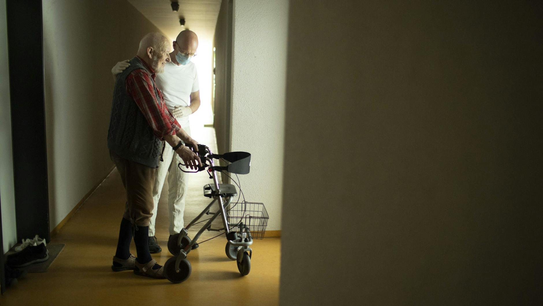 Ein Pfleger hilft einem Mann im Pflegeheim.