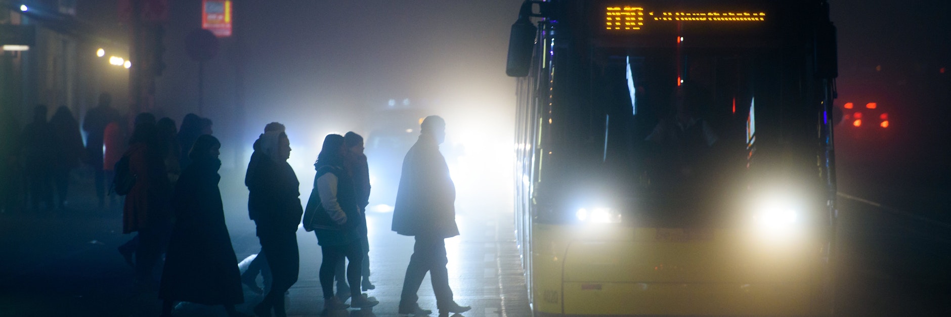 Menschen steigen während neblig-trübem Wetter in Berlin an einer Tram-Haltestelle in eine Straßenbahn (Symbolbild).