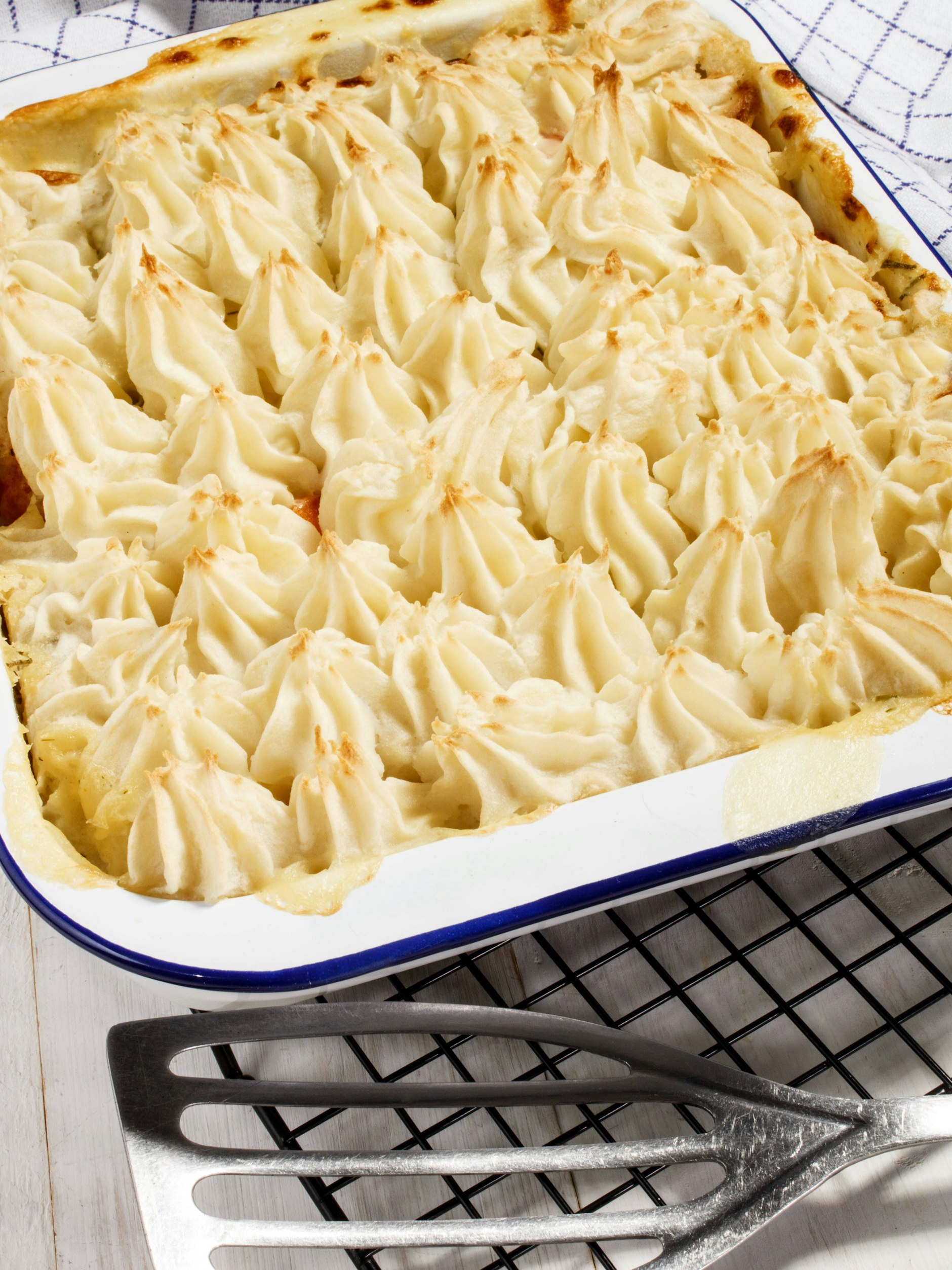 Wer mag, kann den Kartoffelbrei auch mit einem Spritzbeutel kunstvoll auf die Hackfleisch-Schicht spritzen. So wird der Auflauf auch optisch zum Hingucker.