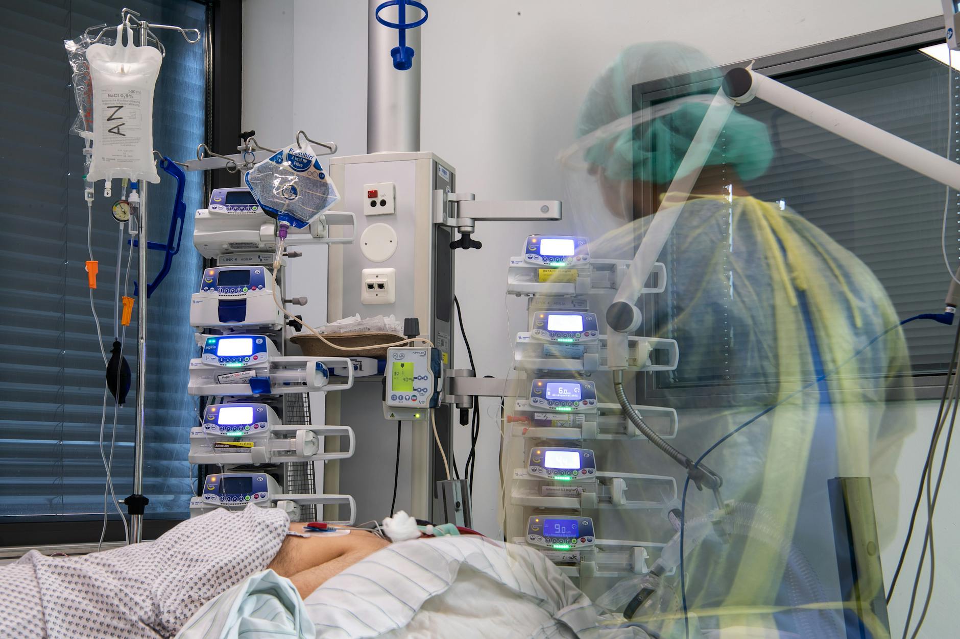 Ein Pfleger steht neben einem Corona-Patienten.