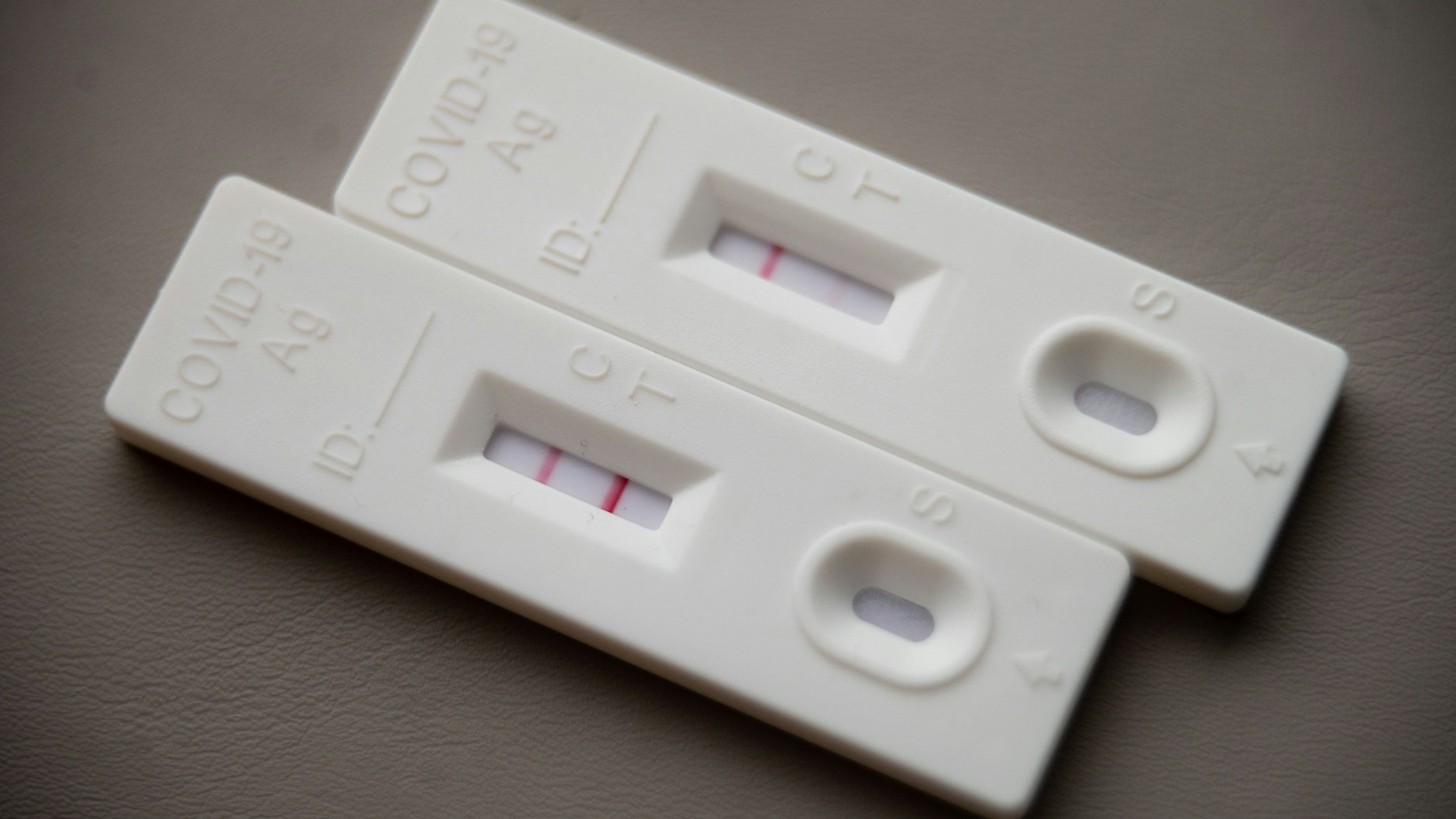 Ein positiver Corona-Selbsttest liegt auf einem Tisch neben einem Corona-Schnelltest, der eine schwach positive Linie hat.