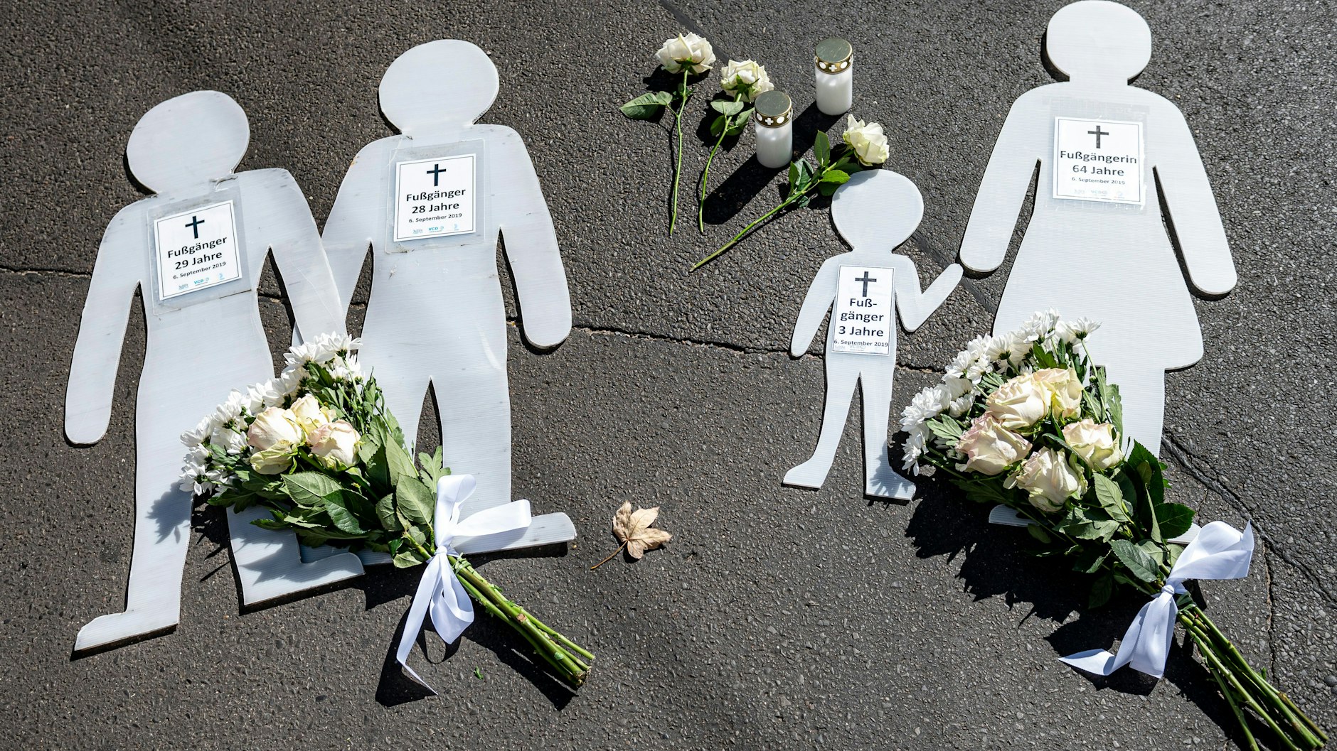 Figuren, die die Opfer darstellen, liegen bei der Mahnwache zum ersten Jahrestag des SUV-Unfalls in der Invalidenstraße am Boden.