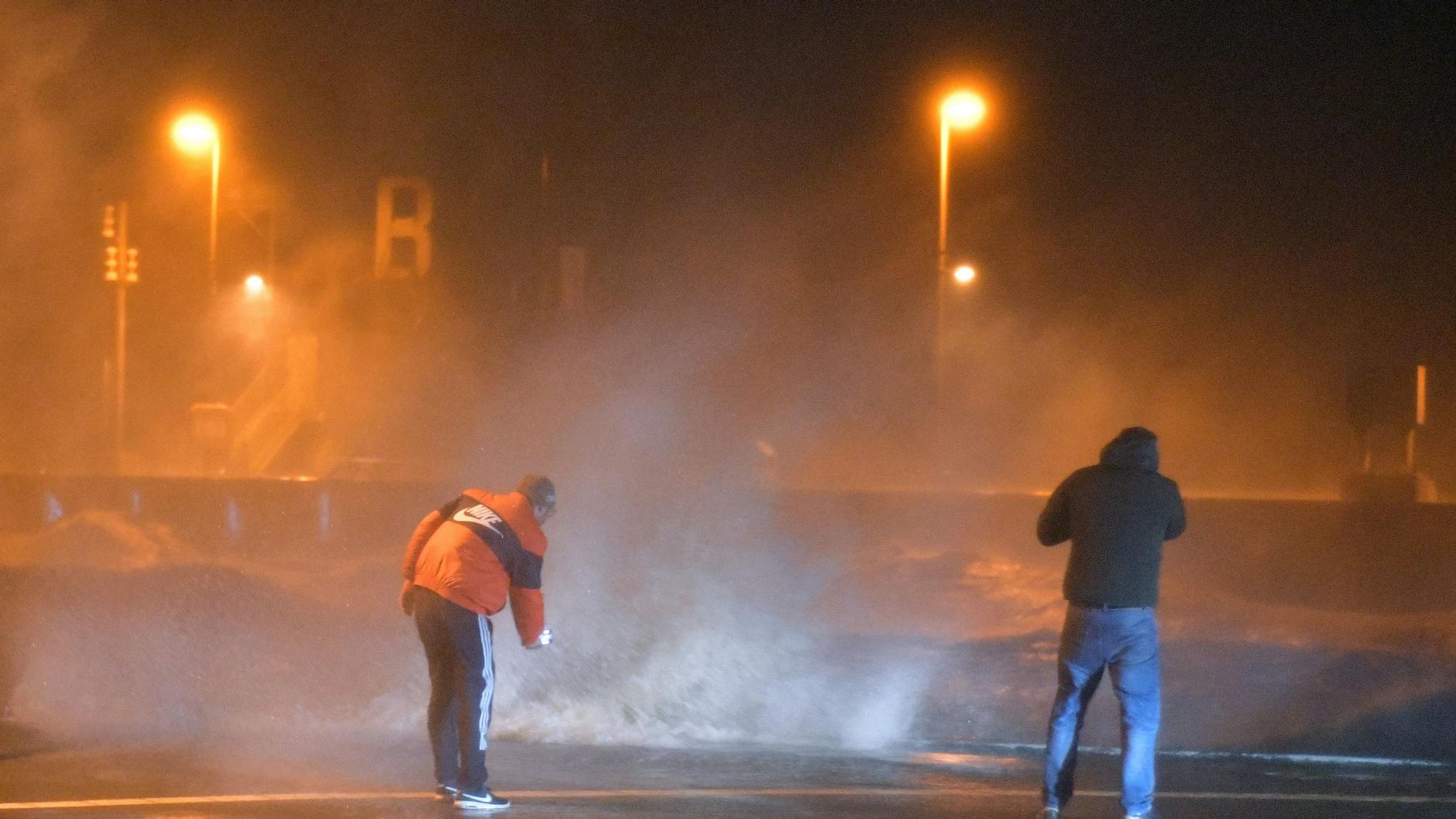 Gefährlich: Schaulustige beobachten Wellen, die in Bremerhaven über die Kaimauer schlagen.