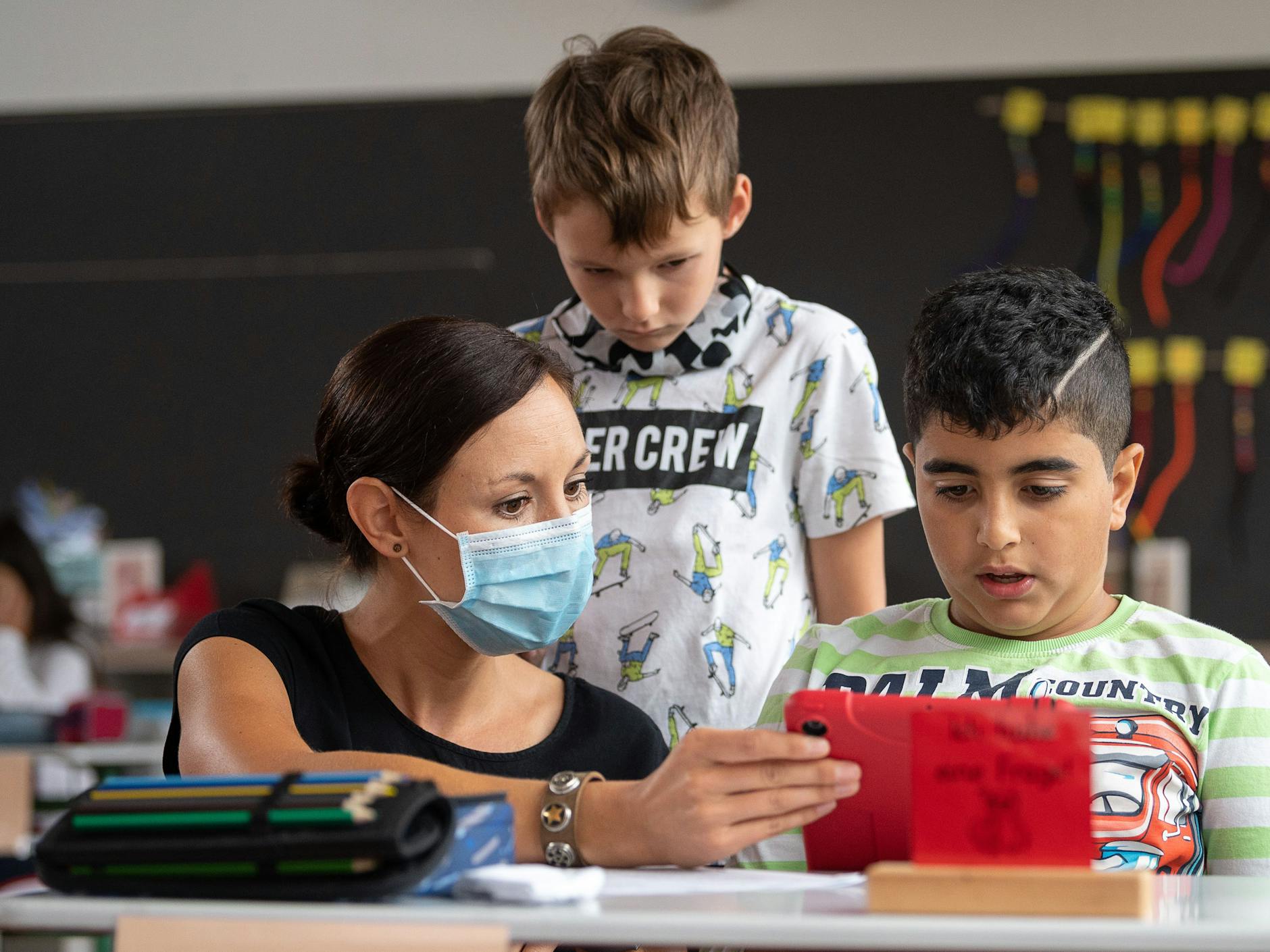 Eine Lehrerin gibt zwei Grundschülern Nachhilfe.