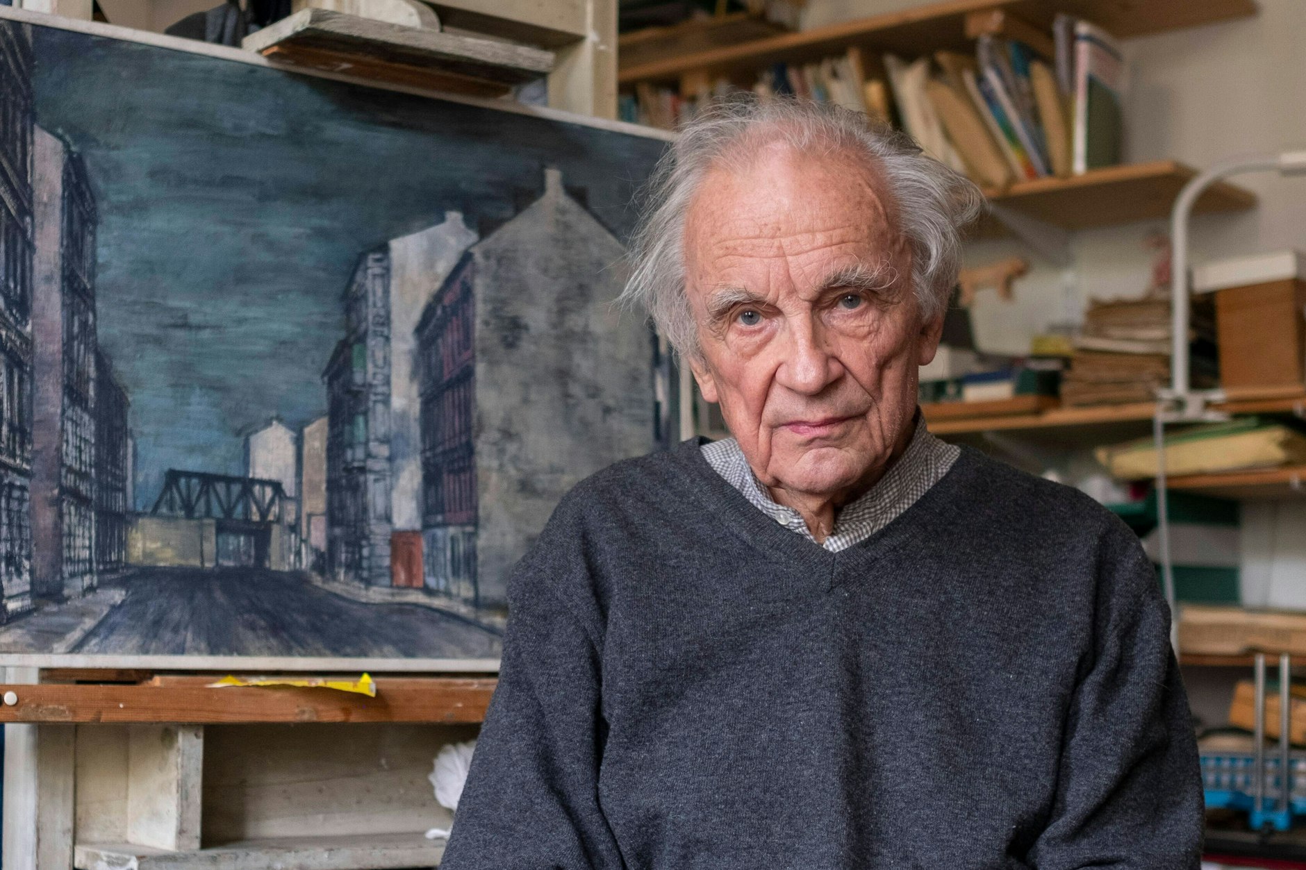 Konrad Knebel (1932-2025) vor einem Bild seiner alten, maroden Berliner Häuserzüge, die es so nicht mehr gibt