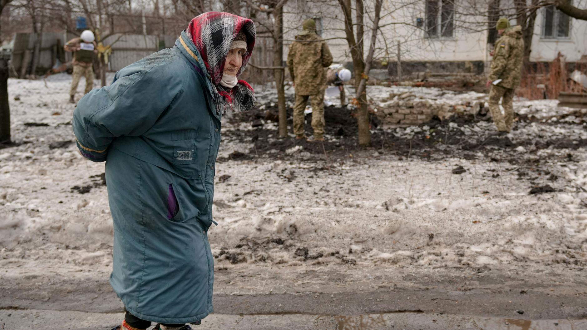 Eine alte Frau geht unweit eines Kraters spazieren.