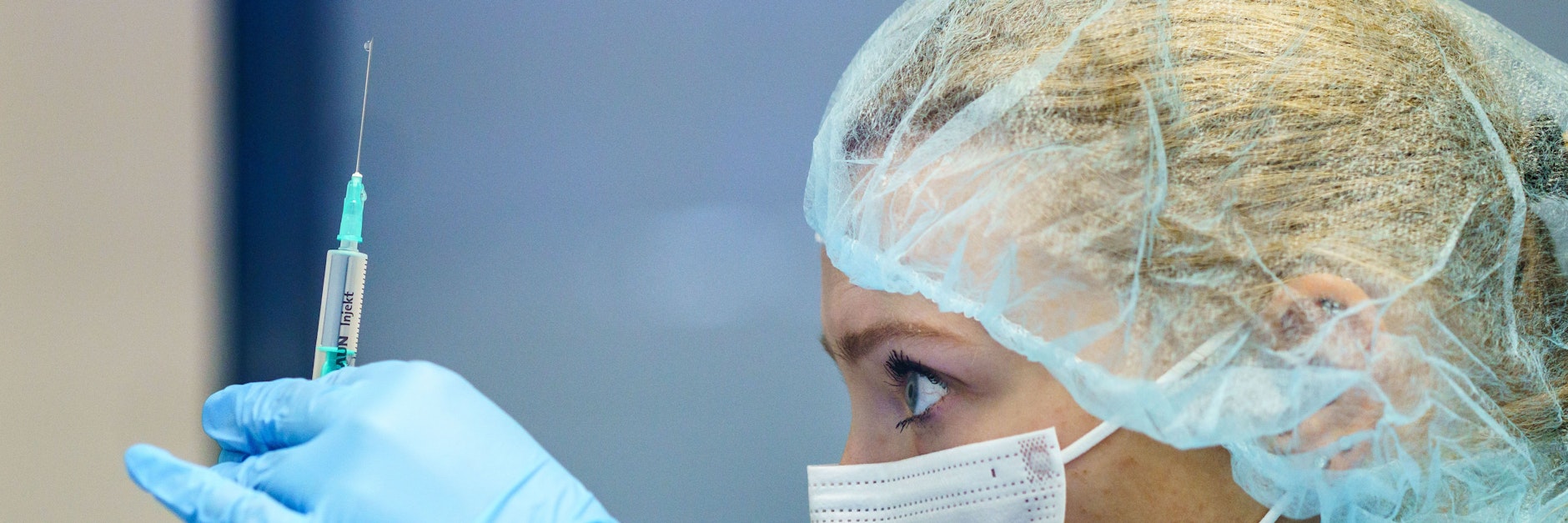 Eine Mitarbeiterin zieht eine Spritze mit dem Impfstoff von Biontech auf.