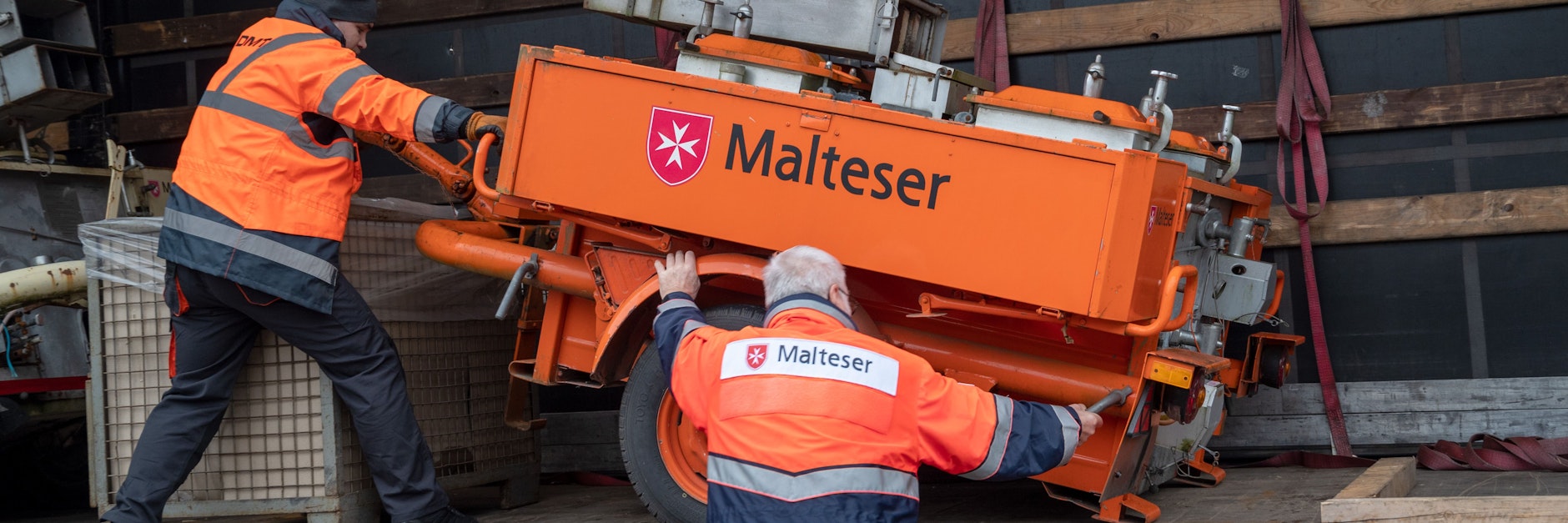 Jürgen Zoltowski (r.) von den Maltesern in Trier verlädt mit einem LKW-Fahrer eine Feldküche in einen LKW, der mit weiteren Hilfsgütern wie Feldküchen und medizinischem Material der Caritas-Werkstätten in die Ukraine gebracht wird.