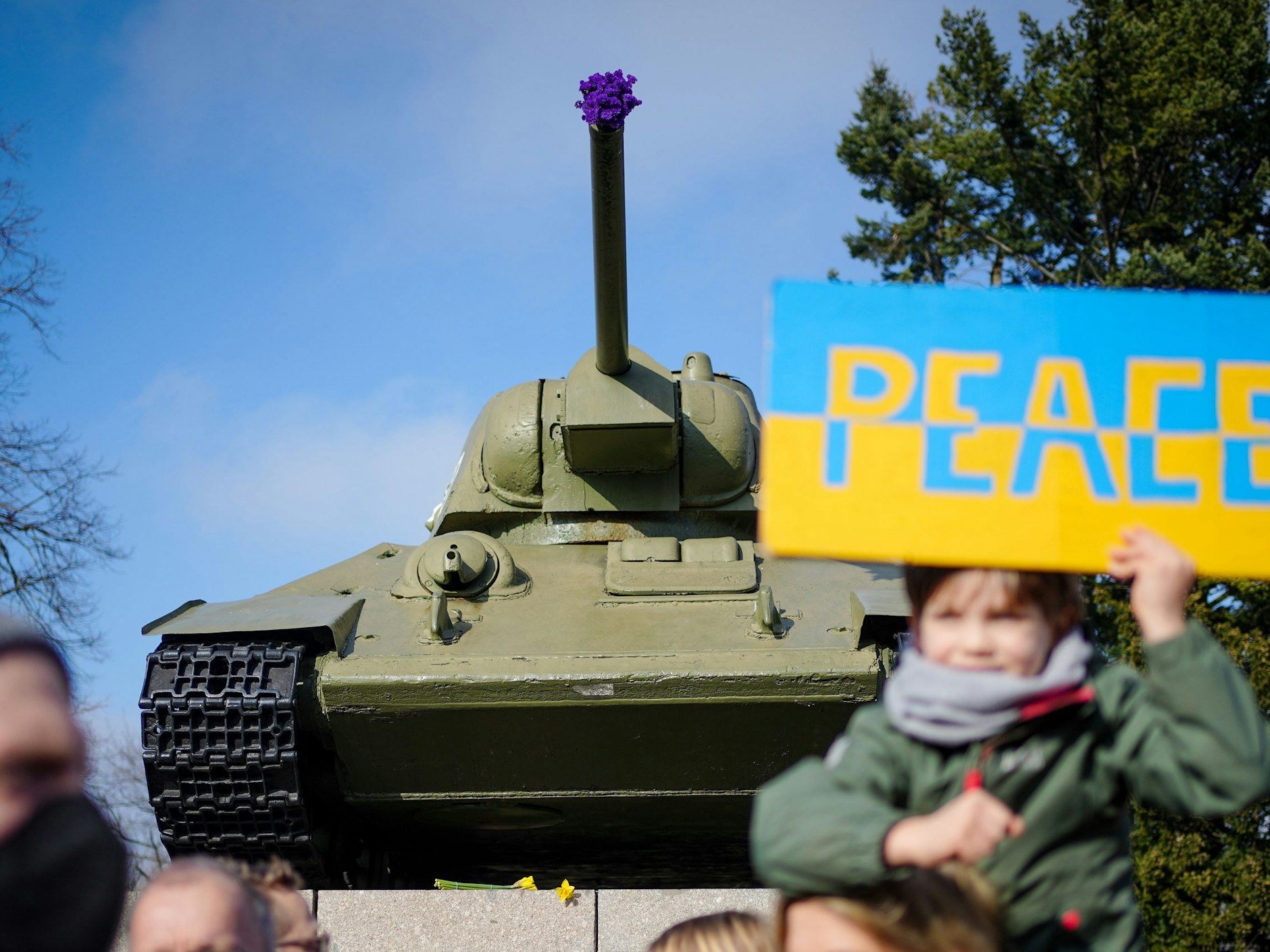 Eine bizarre Situation: Ein Kind hält ein Schild „Peace“ vor einem Panzer des sowjetischen Ehrenmals hoch, in dessen Kanone Blumen stecken.