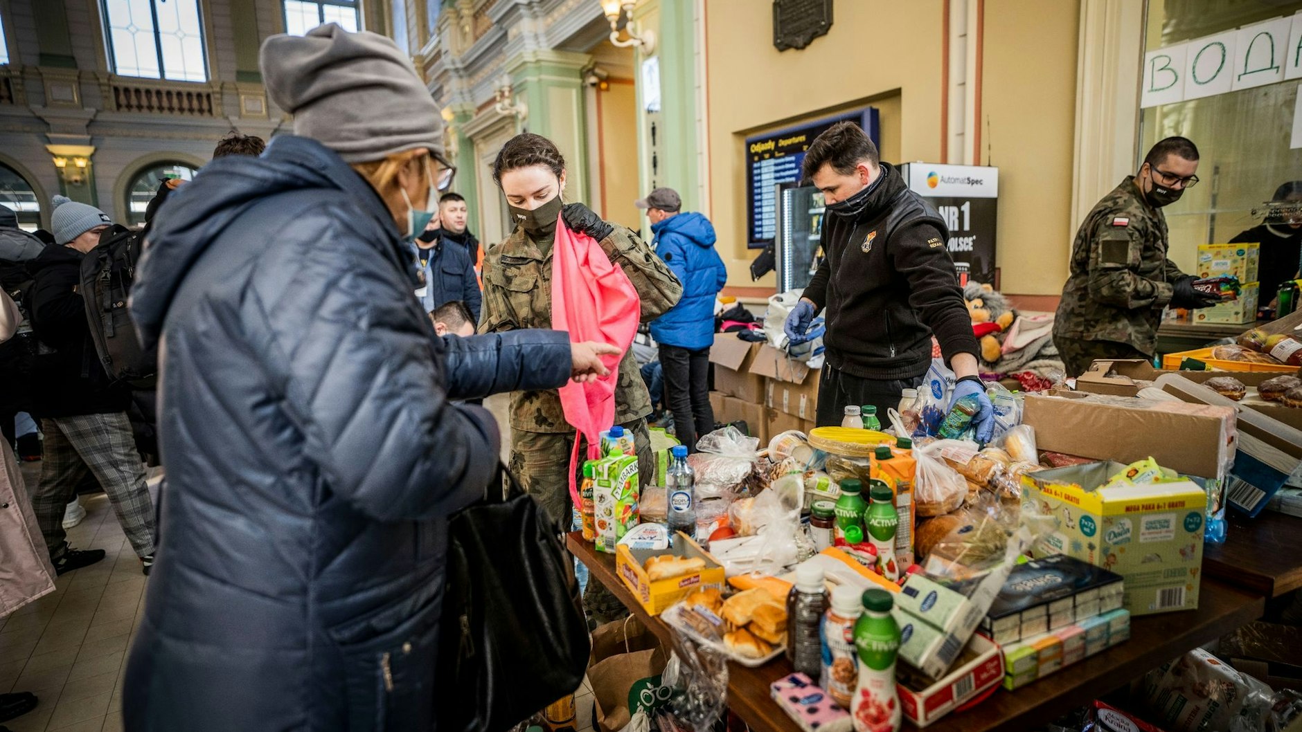 Helfer verteilen Lebensmittel und Süßigkeiten an Geflüchtete am Bahnhof von Przemysl.