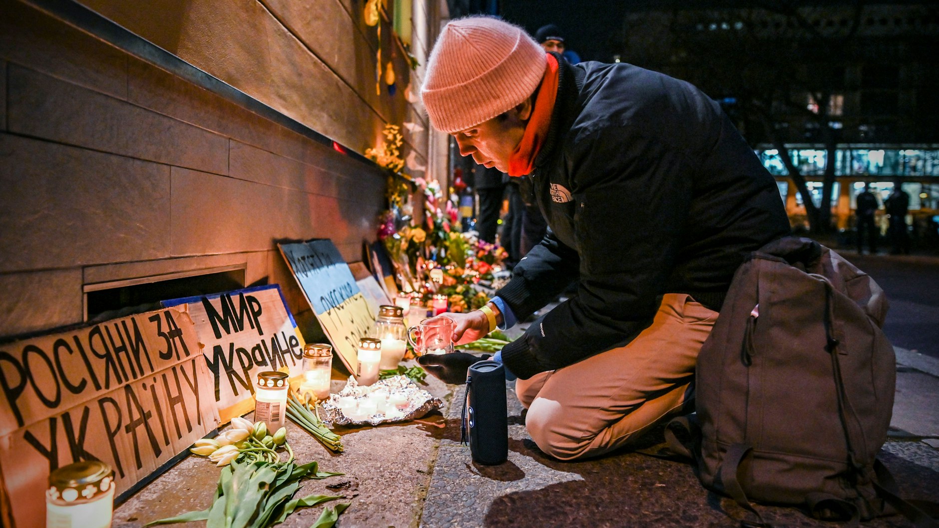 Der Regisseur Peter Cant zündet an der Wand der ukrainischen Botschaft Kerzen an.