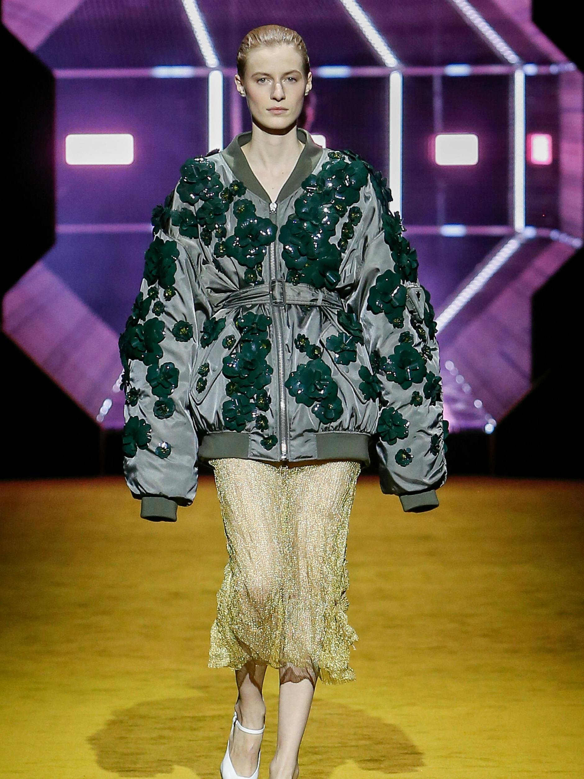 Der Aufmacher-Look der Prada-Show war möglicherweise kein Zufall, einen Tag zuvor hatte der Krieg in der Ukraine begonnen. Model Julia Nobis trägt eine Bomberjacke, die mit Blumen bestickt ist.