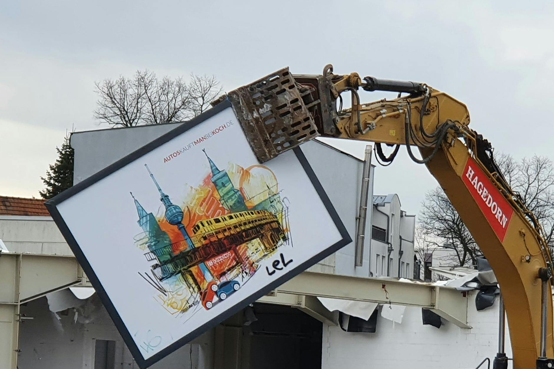 Fast liebevoll entfernt der Abrissbagger ein großes Plakat vom Gebäude.