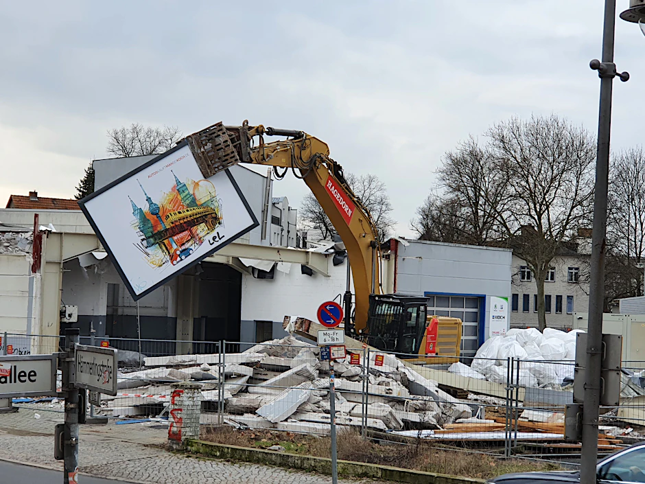 Fast liebevoll entfernt der Abrissbagger ein großes Plakat vom Gebäude.