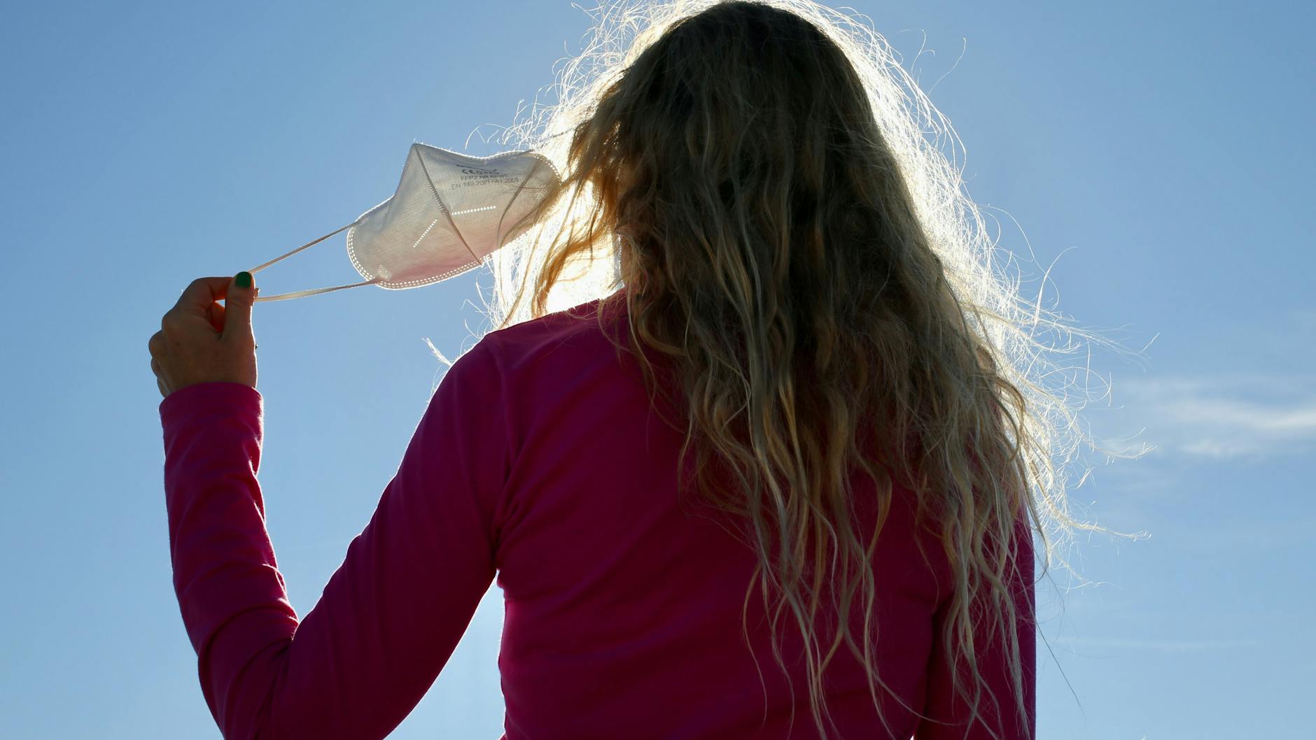 Eine Frau nimmt sich in Madrid die Corona-Maske ab.