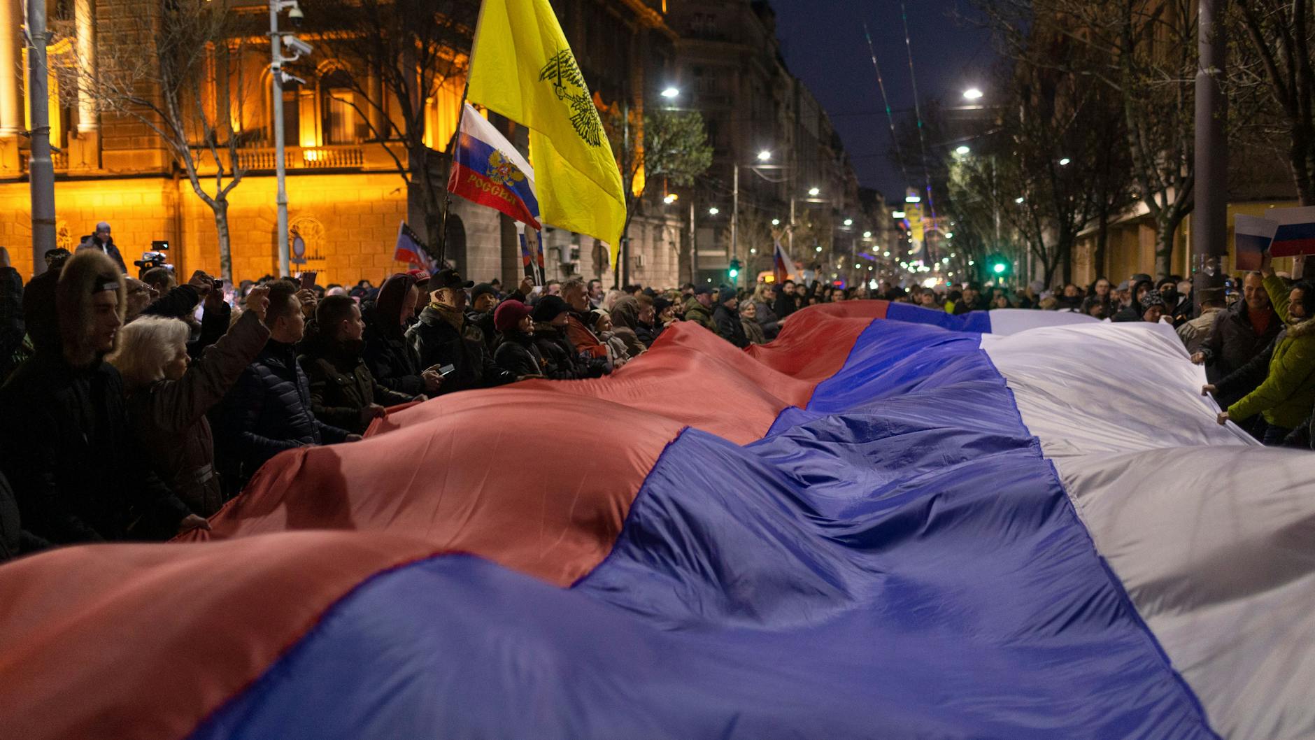 Demonstranten halten eine große russische Fahne während der Kundgebung in Belgrad.