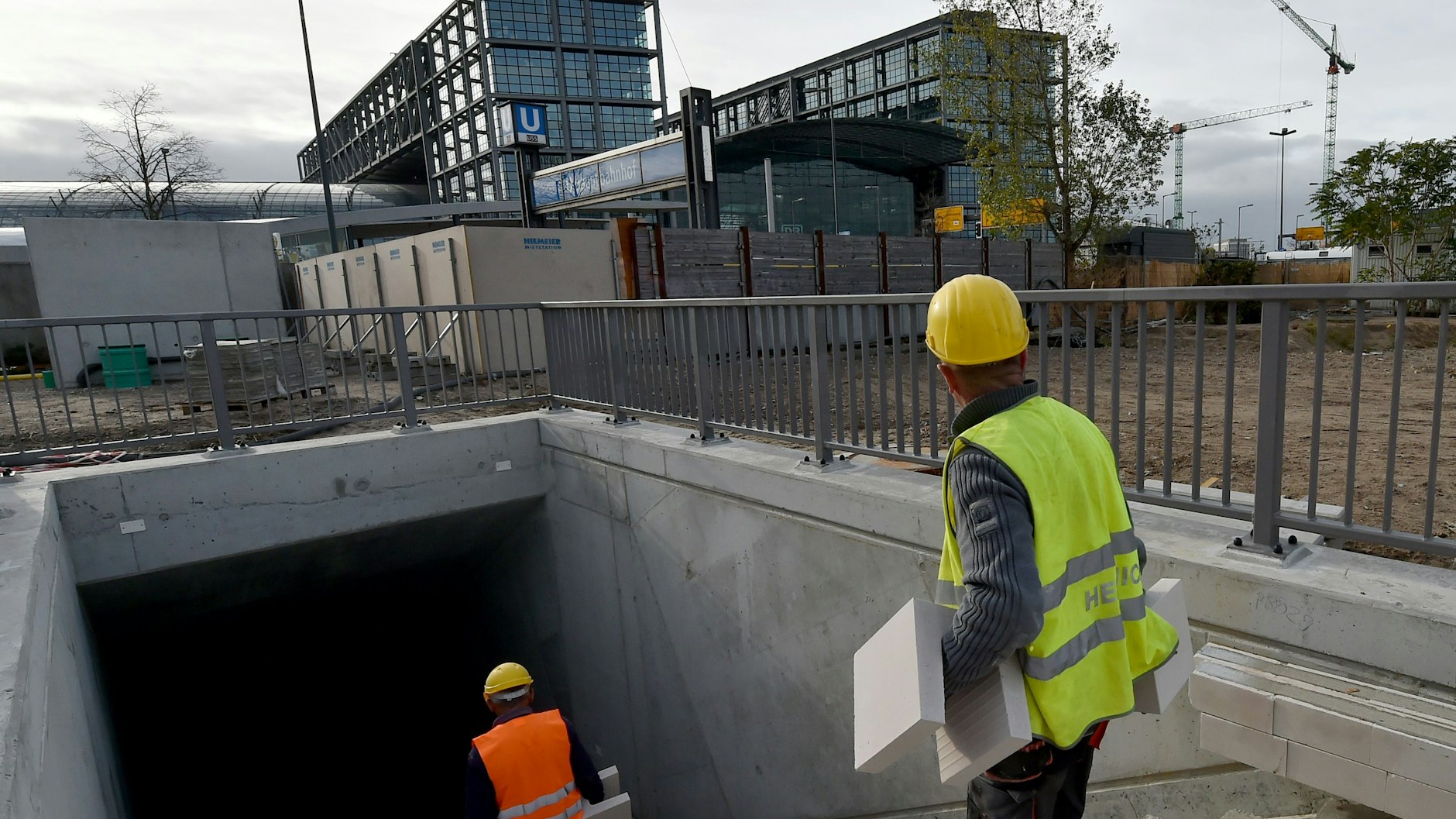 Zwei Bauleute steigen die Treppe zum provisorischen Endbahnhof nördlich der Invalidenstraße hinab. Im Hintergrund ist der Berliner Hauptbahnhof zu sehen. Ein Archivbild von 2018.