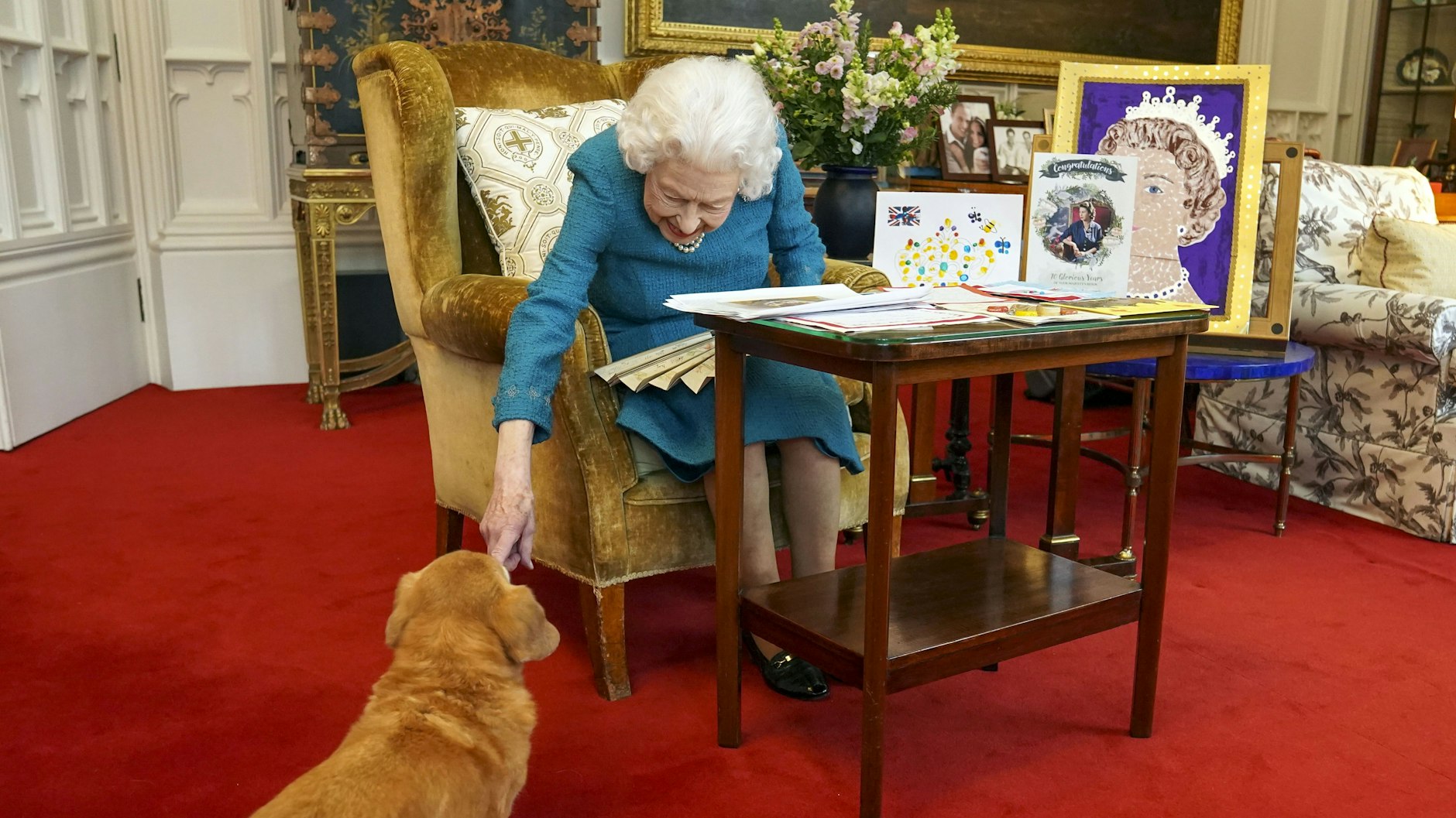 Königin Elizabeth II. streichelt einen ihrer Hunde, einen Corgi namens Candy, während sie im Oak Room von Schloss Windsor zwischen Erinnerungsstücken sitzt.