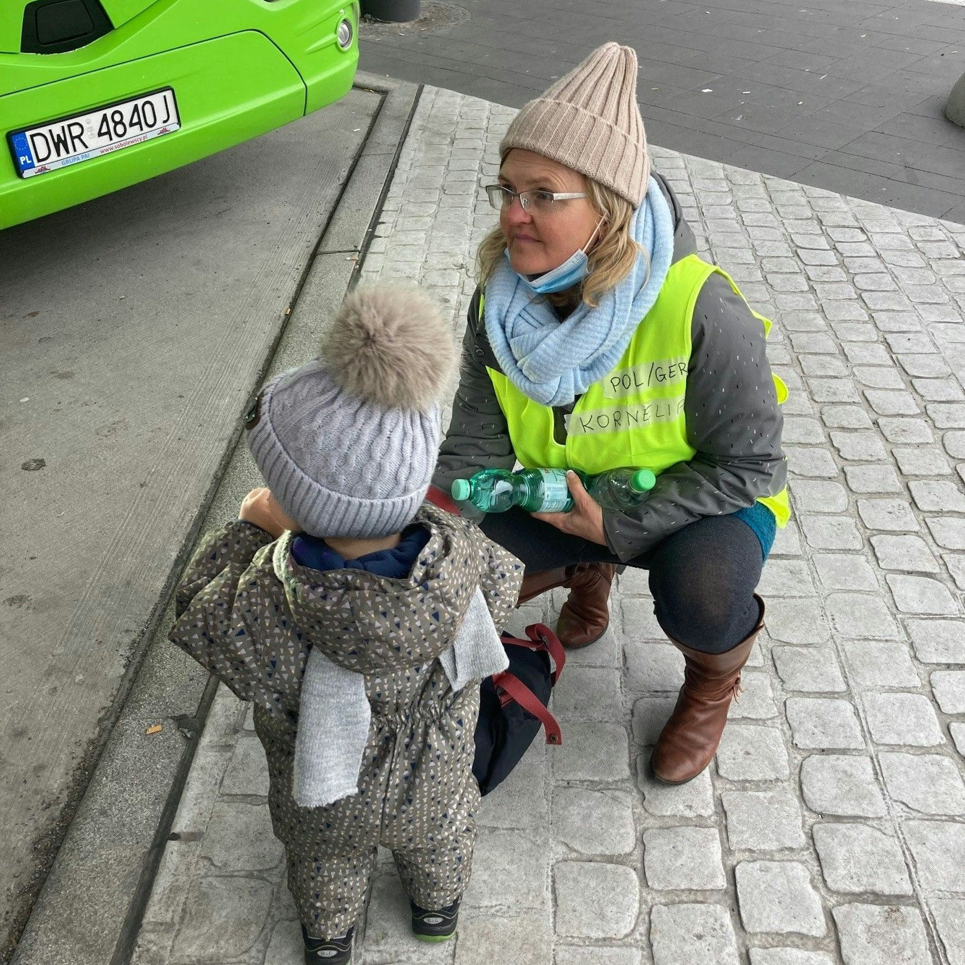 Eine ehrenamtliche Helferin kümmert sich um ein ukrainisches Kind, das mit seiner Mutter aus dem Bus gestiegen ist.