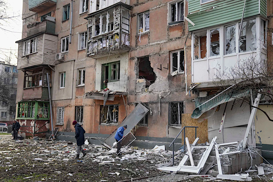 Mariupol: Menschen vor einem von Granaten getroffenen Wohnhaus. Der Generalbundesanwalt in Karlsruhe ermittelt nun wegen möglicher russischer Kriegsverbrechen in der Ukraine.